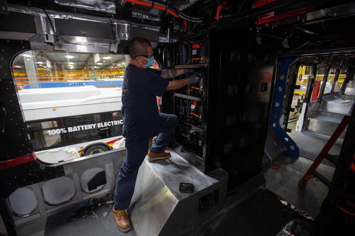 A worker installs electrical batteries in a bus at the BYD electric bus factory in Lancaster, California