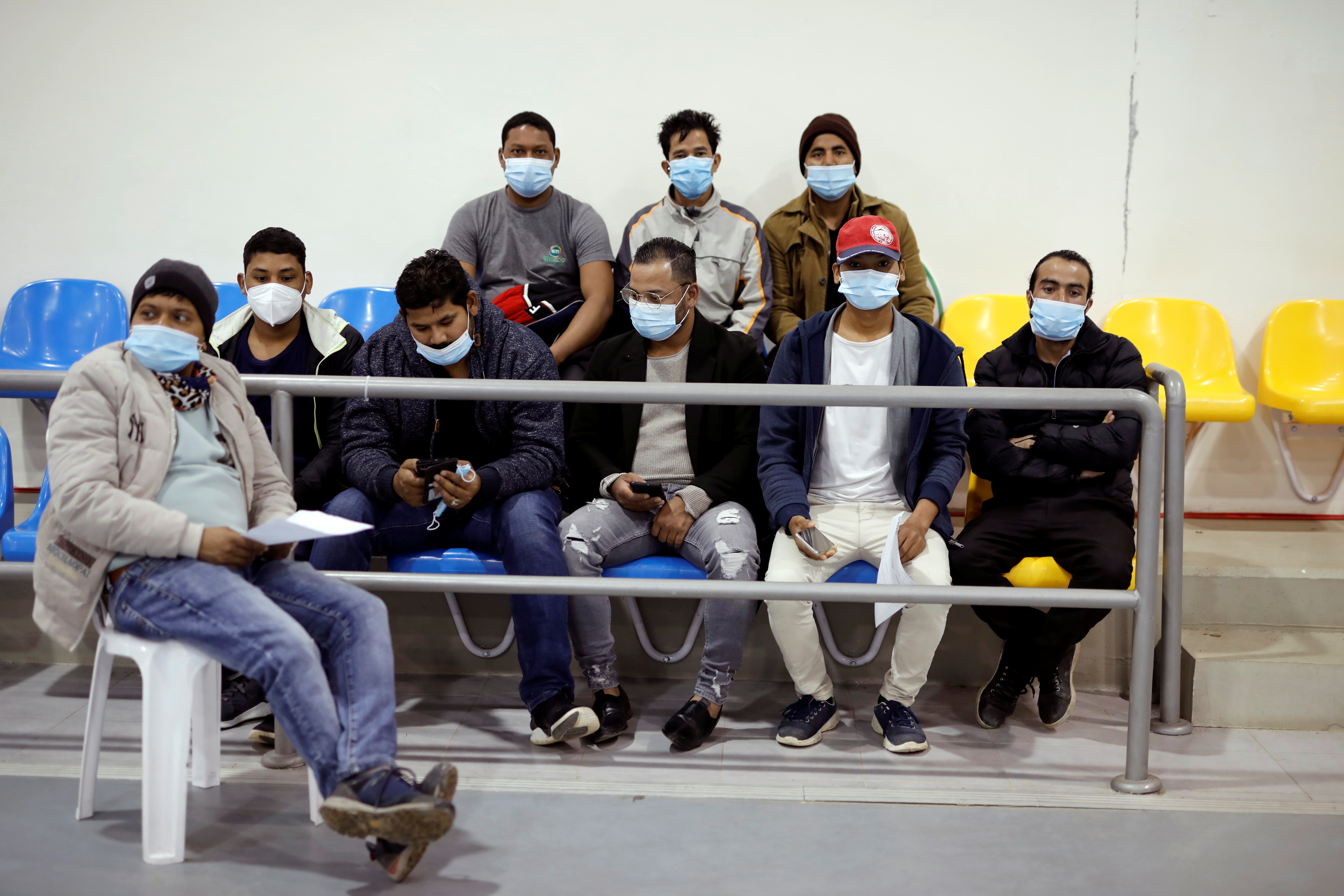 A group of agricultural workers from Nepal wait after receiving a vaccination against the coronavirus disease (COVID-19) at a temporary Clalit healthcare maintenance organisation (HMO) centre, at a sports hall in Netivot