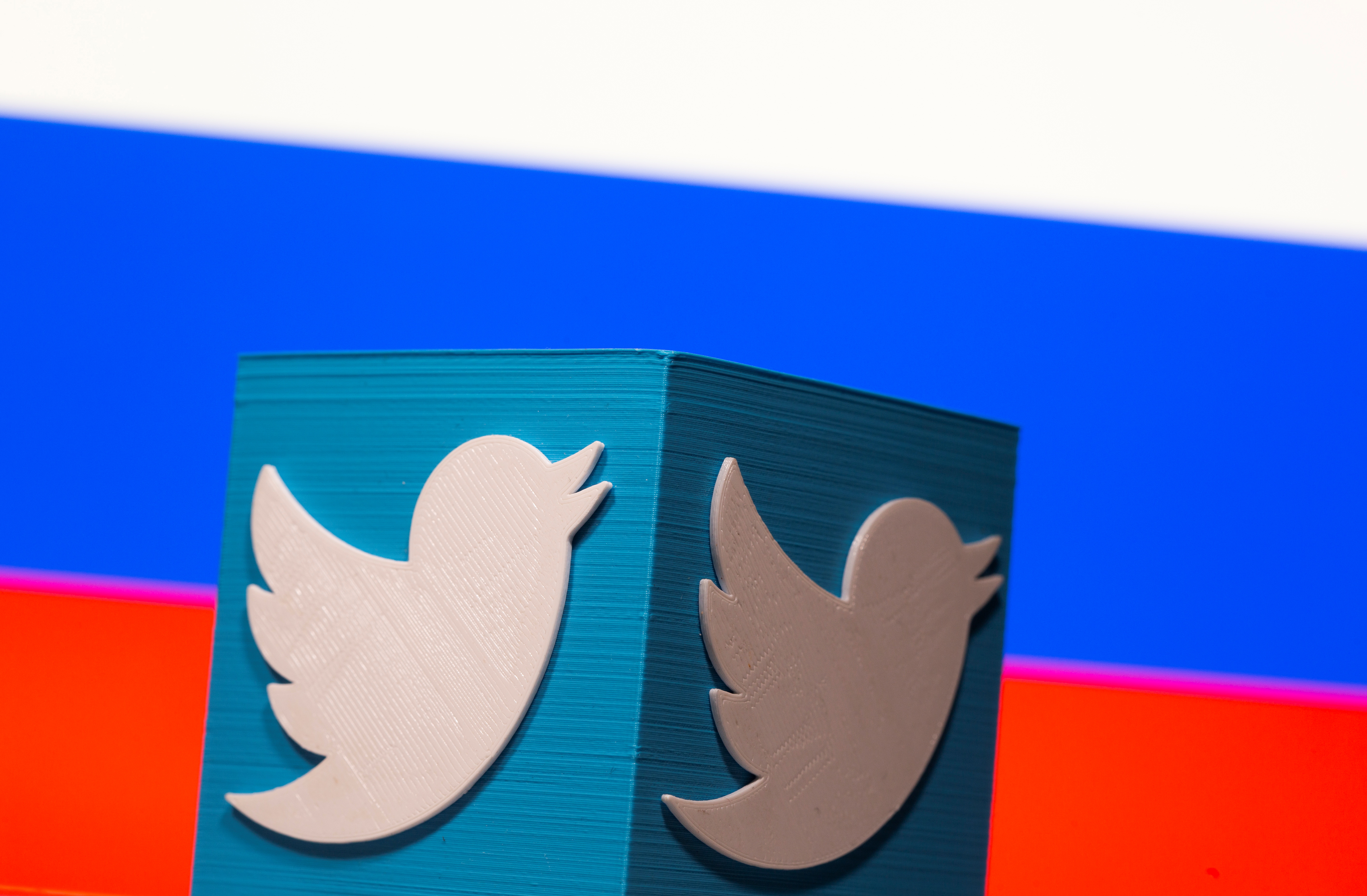 A 3D-printed Twitter logo is pictured in front of a Russian flag in this illustration