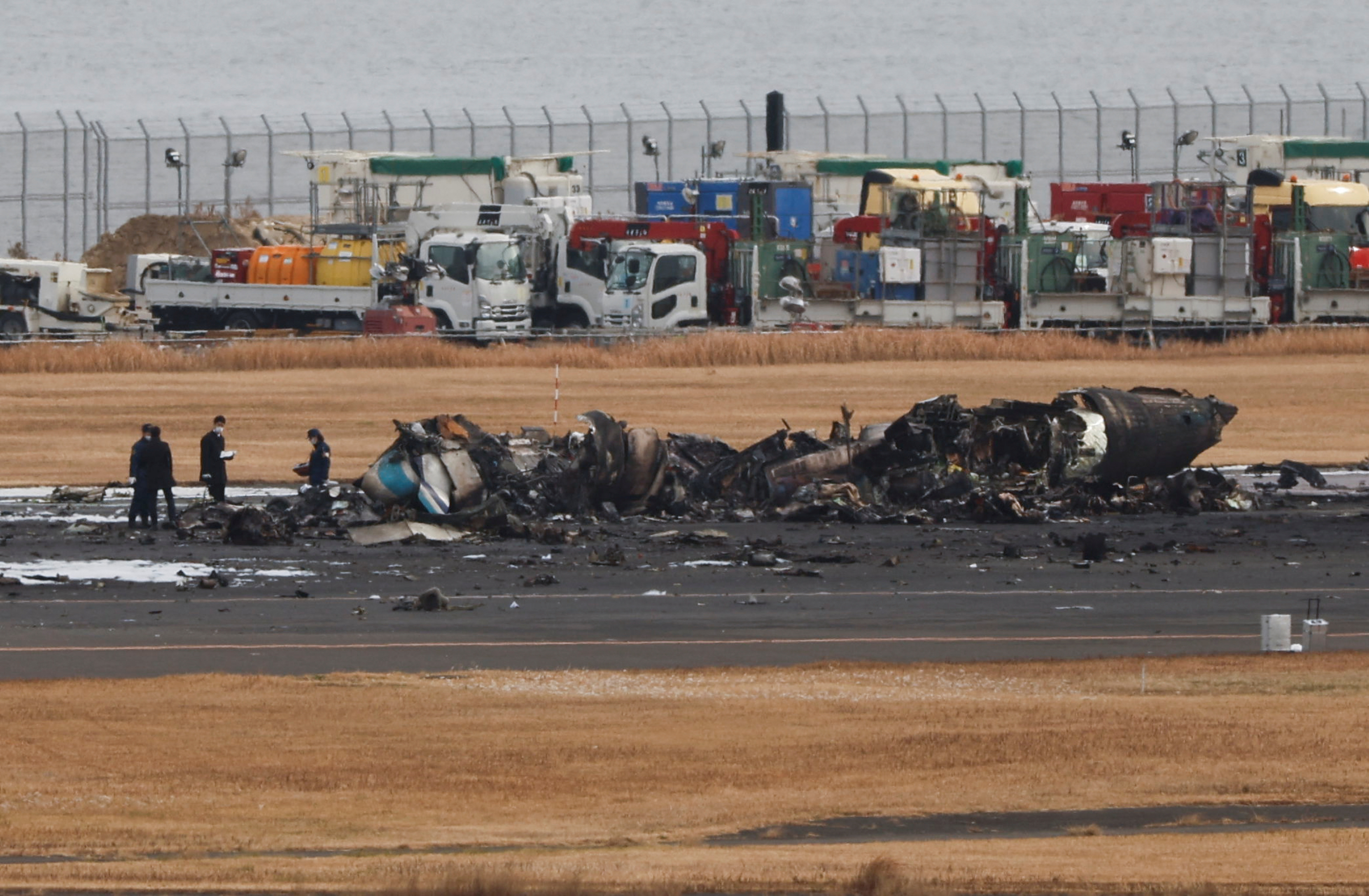 Officials investigate a burnt Japan Coast Guard aircraft after a collision with Japan Airlines' (JAL) Airbus A350 plane in Tokyo