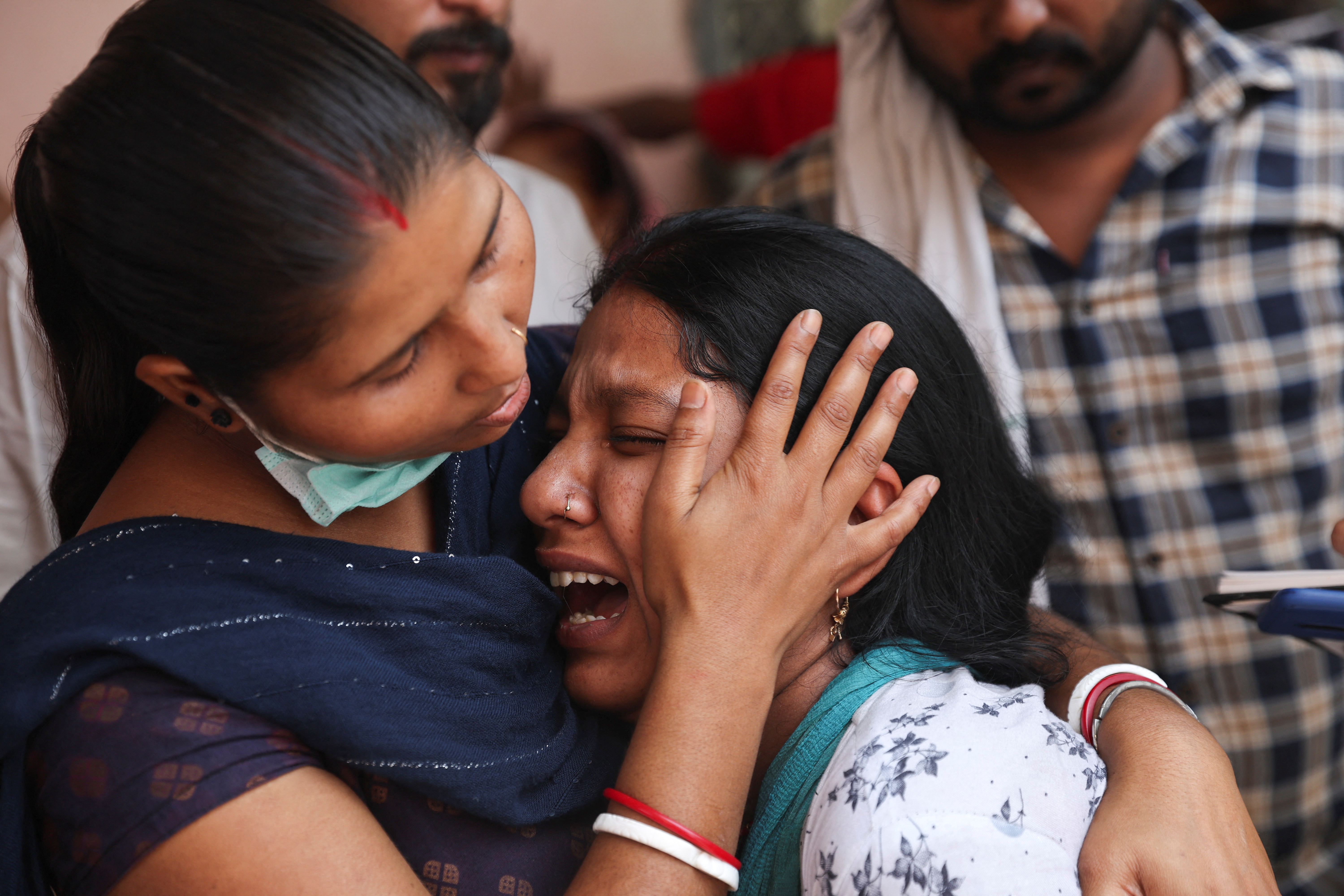 Woman consoles her neighbour after her mother died in the fire that broke out in a commercial building in New Delhi