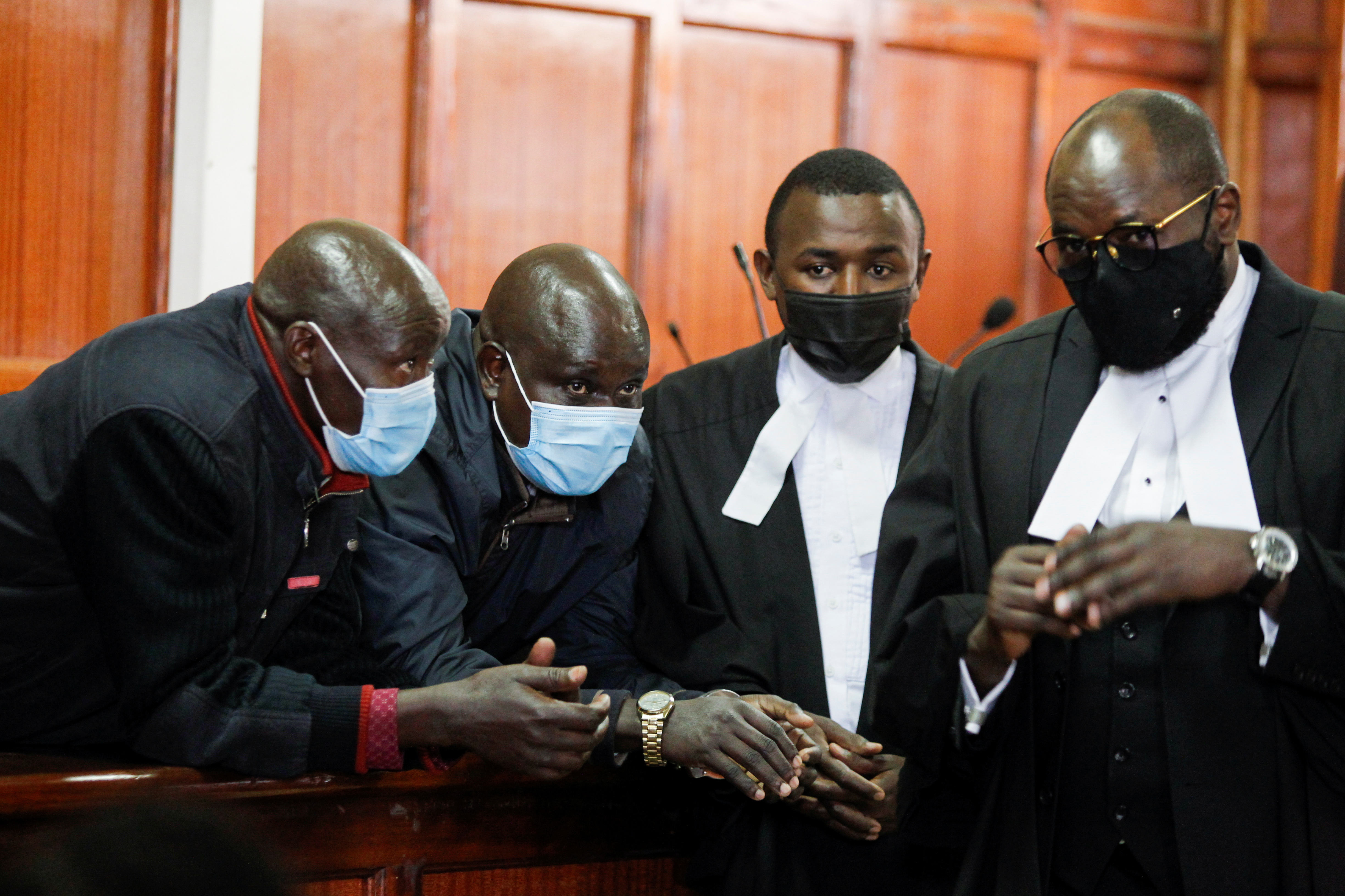 Former Kenyan police officers talk to their lawyers at Milimani Law courts in Nairobi