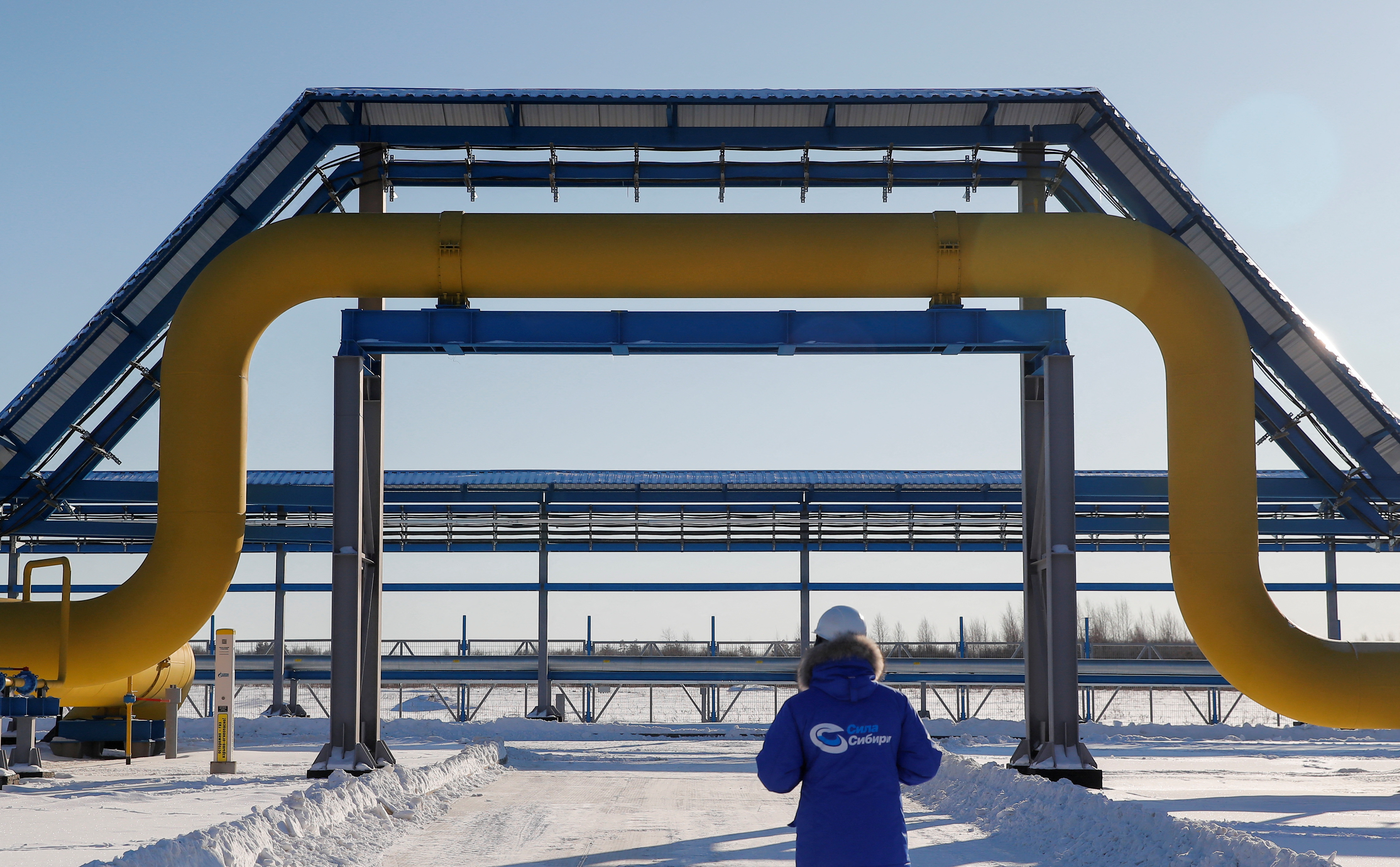 An employee walks past a part of Gazprom's Power Of Siberia gas pipeline at the Atamanskaya compressor station outside the far eastern town of Svobodny