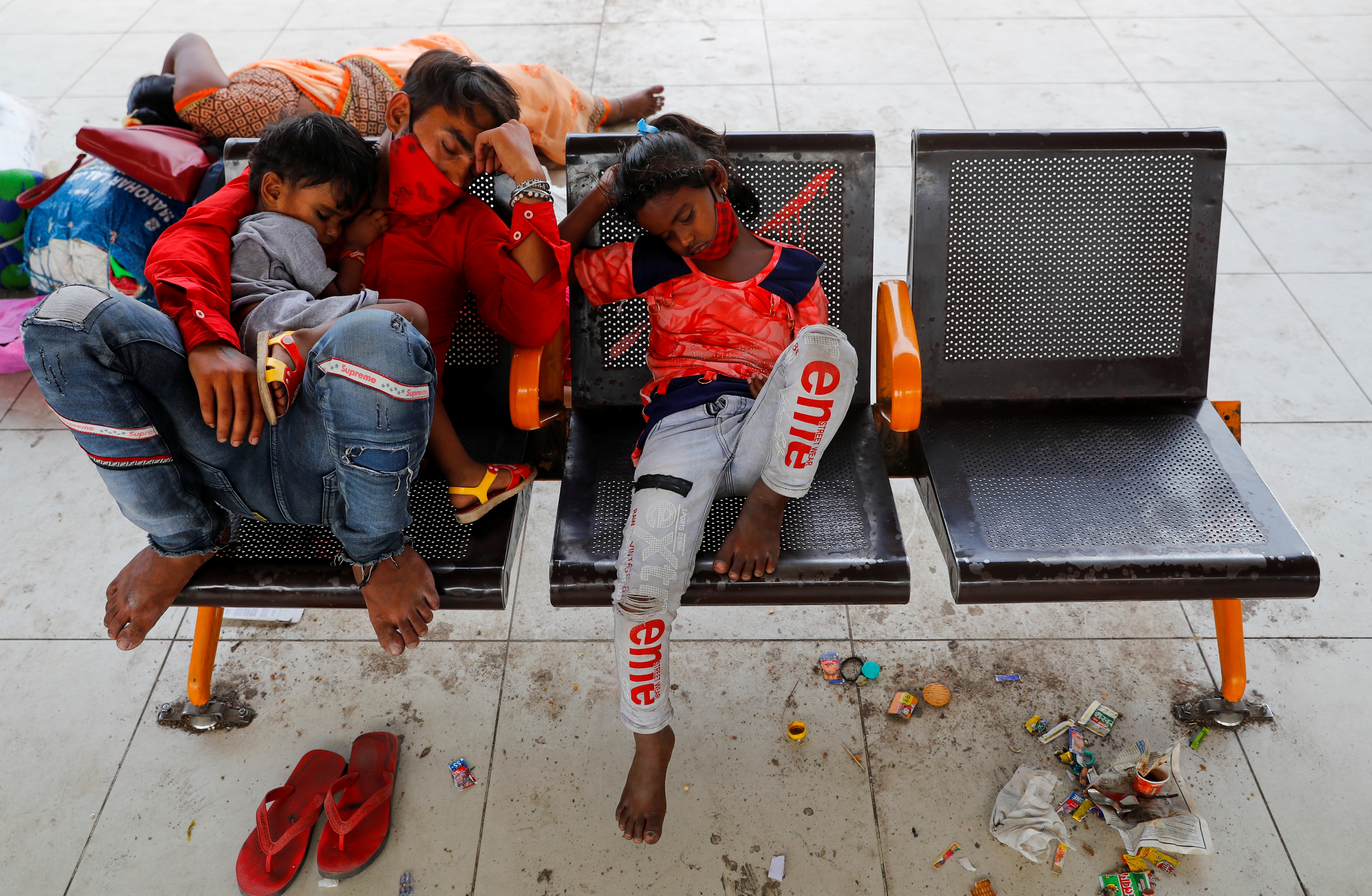 A migrant worker and his children sleep at a bus station as they wait to return to their village, after Delhi government ordered a six-day lockdown to limit the spread of the coronavirus disease (COVID-19), in Ghaziabad on the outskirts of New Delhi, India, April 20, 2021. REUTERS/Adnan Abidi