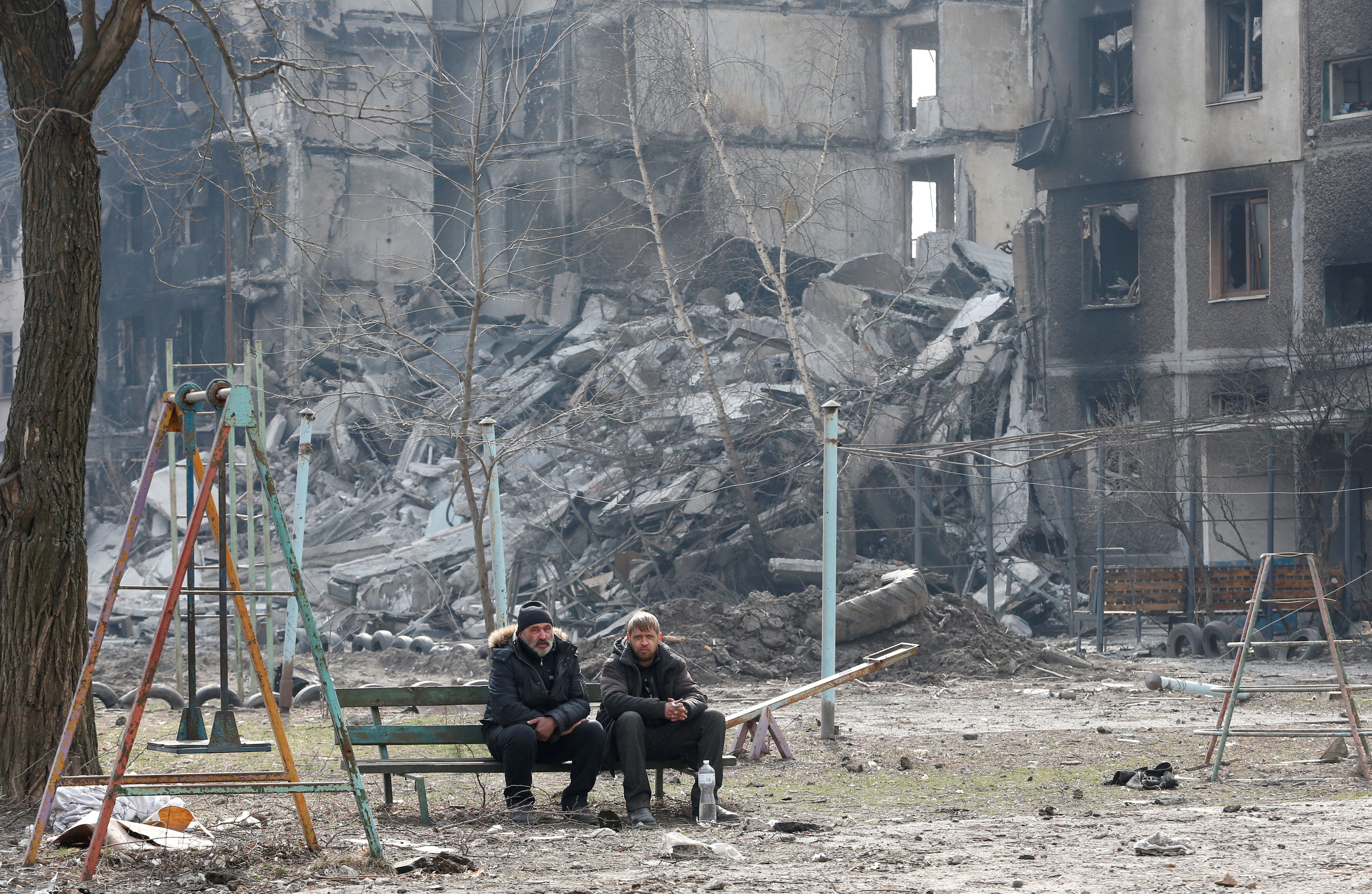 Local residents sit on a bench in the besieged city of Mariupol