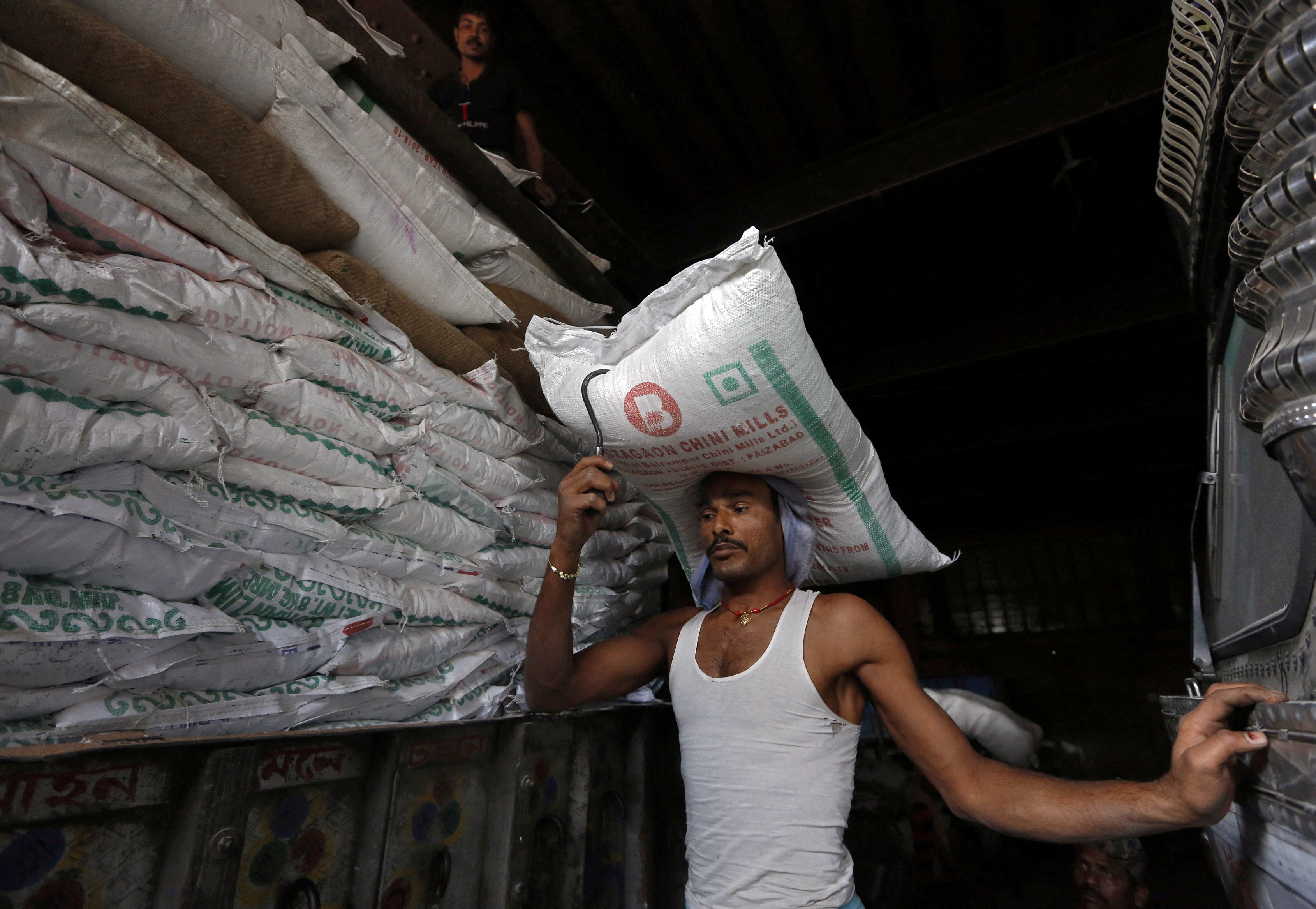 A labourer carries a sack of sugar to load it onto a supply truck in Kolkata, India