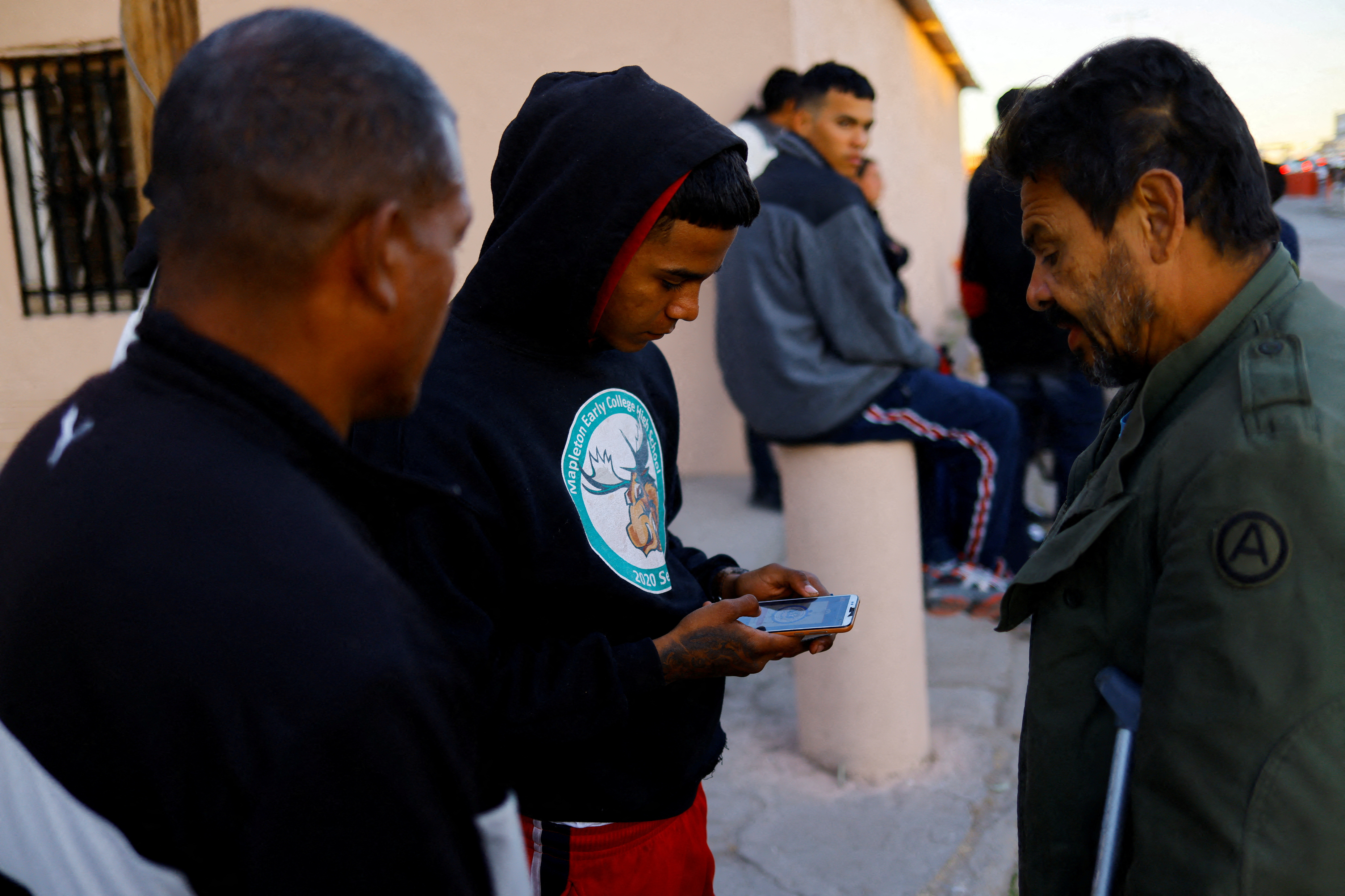 Migrants seeking asylum in the U.S. use their phones to request an appointment at a land port of entry to the U.S., in Ciudad Juarez