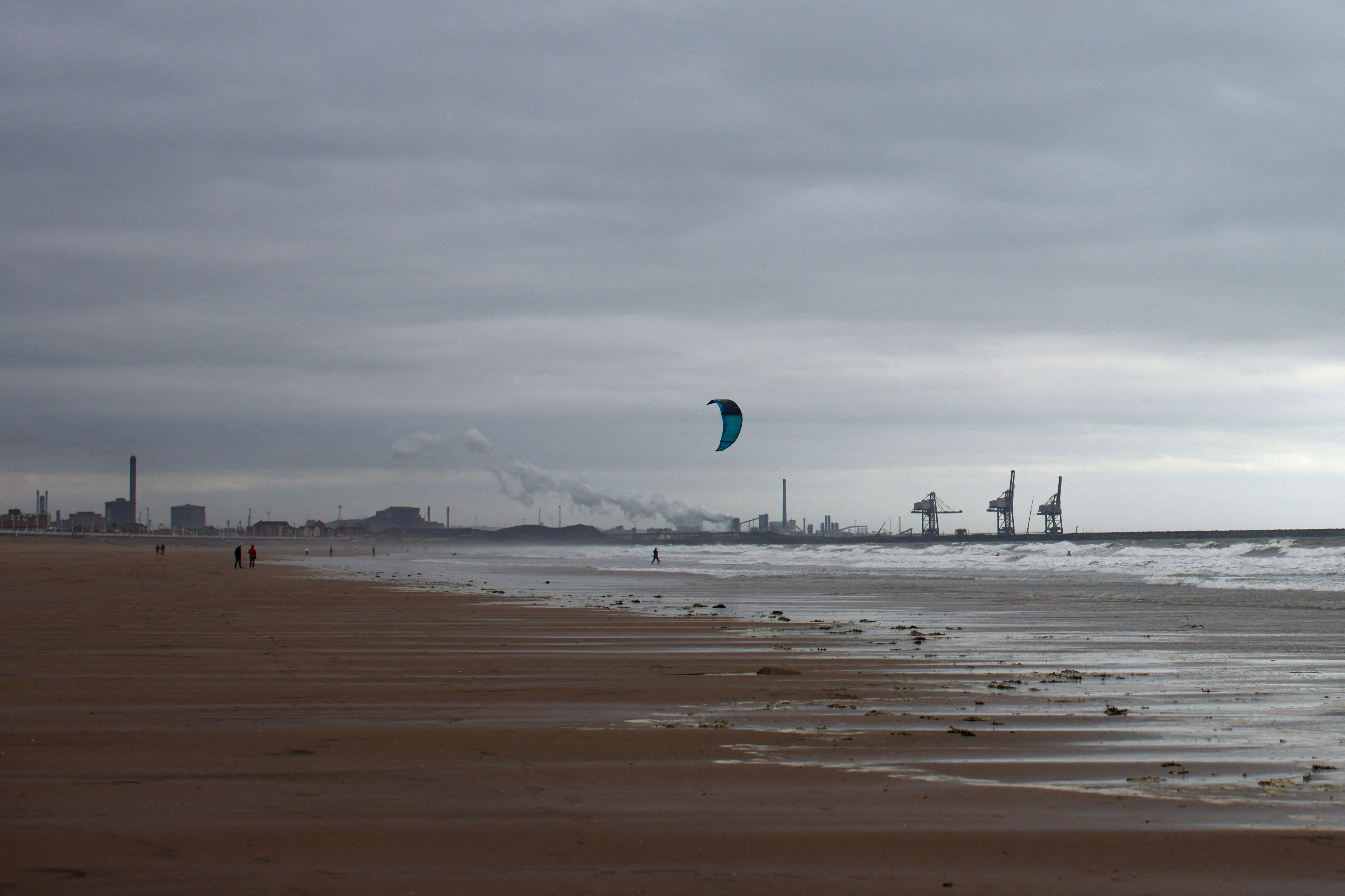 A kite surfer rides in front of a steel factory in Port Talbot