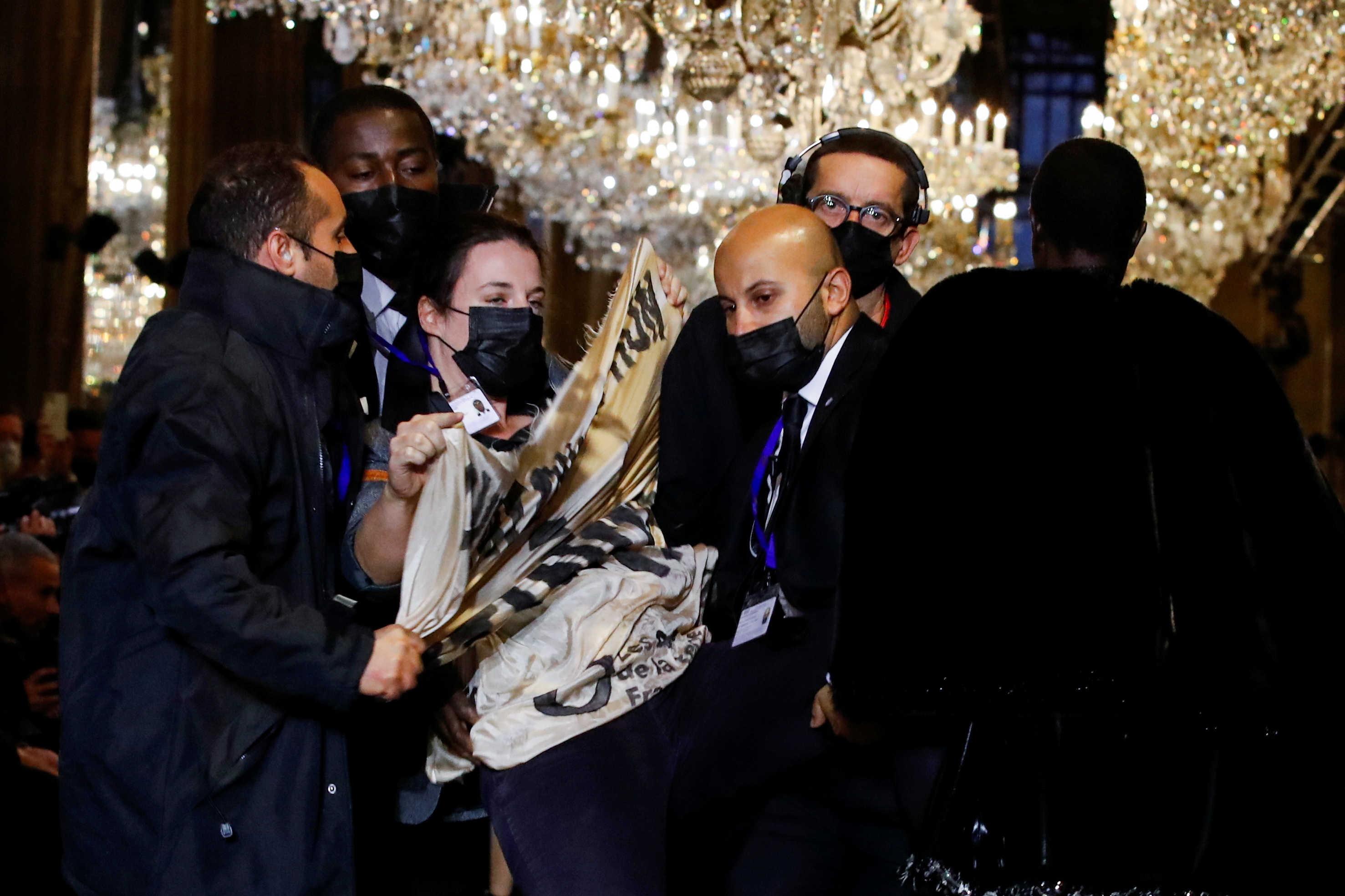 Security personnel remove an activist belonging to the 'Les Amis de la Terre France' or 'Friends of the Earth - France' , who crashed the designer Nicolas Ghesquiere Spring/Summer 2022 women's ready-to-wear collection show for fashion house Louis Vuitton during Paris Fashion Week in Paris, France, October 5, 2021. REUTERS/Gonzalo Fuentes 