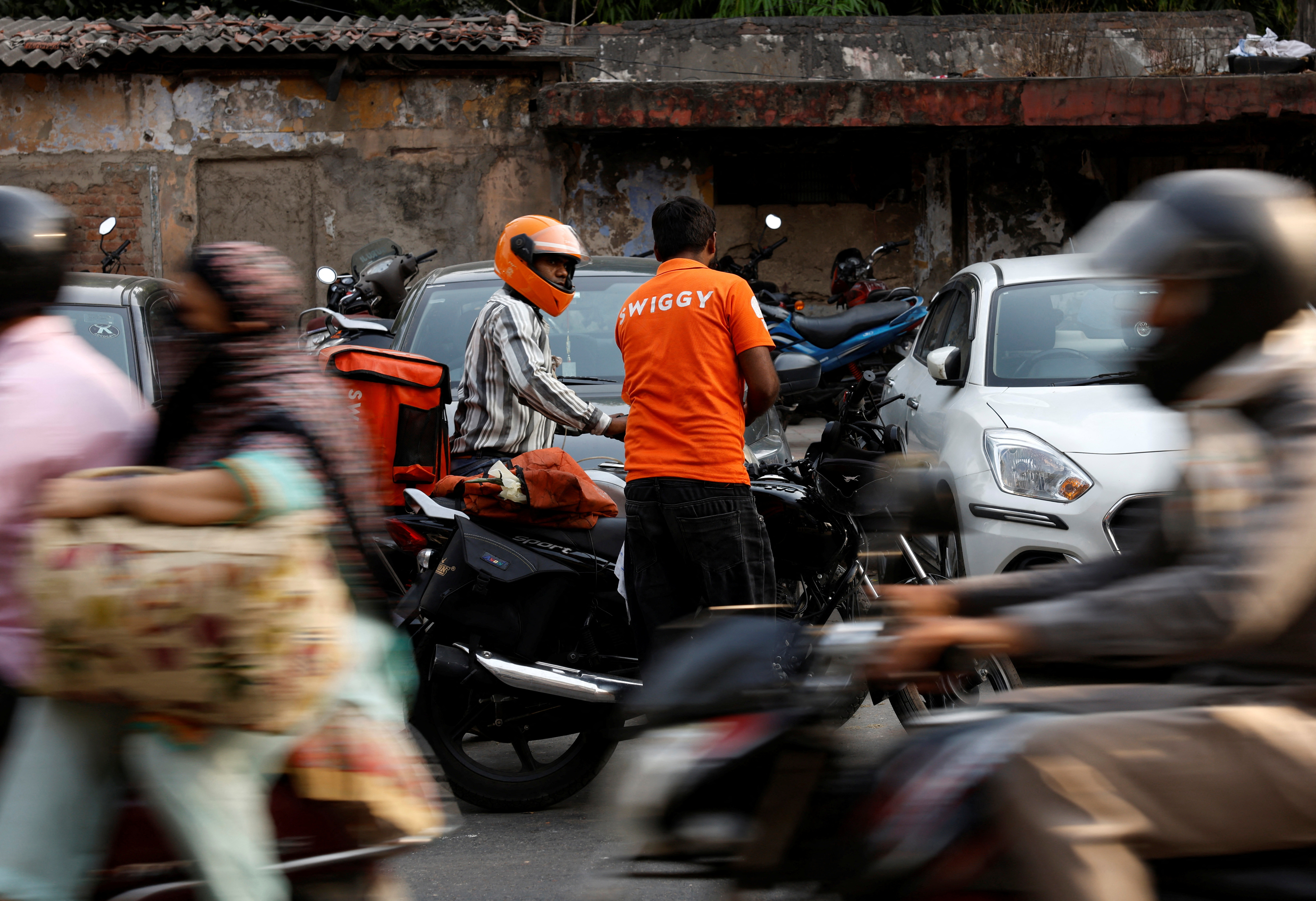 Gig workers prepare to get the orders delivered after picking them up from Swiggy's grocery warehouse, in New Delhi