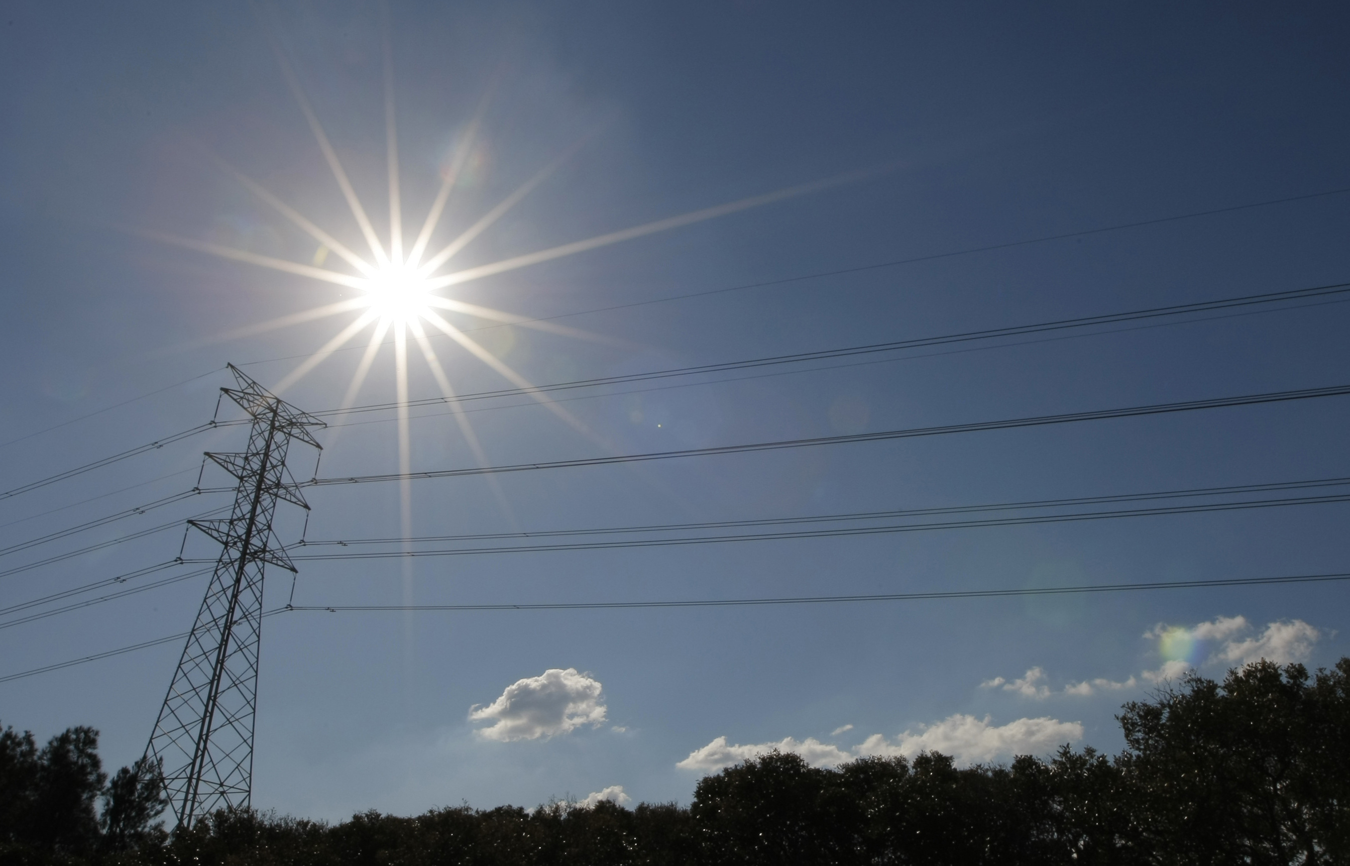 Sun shines over a high tension power line in an industrial area of Sydney