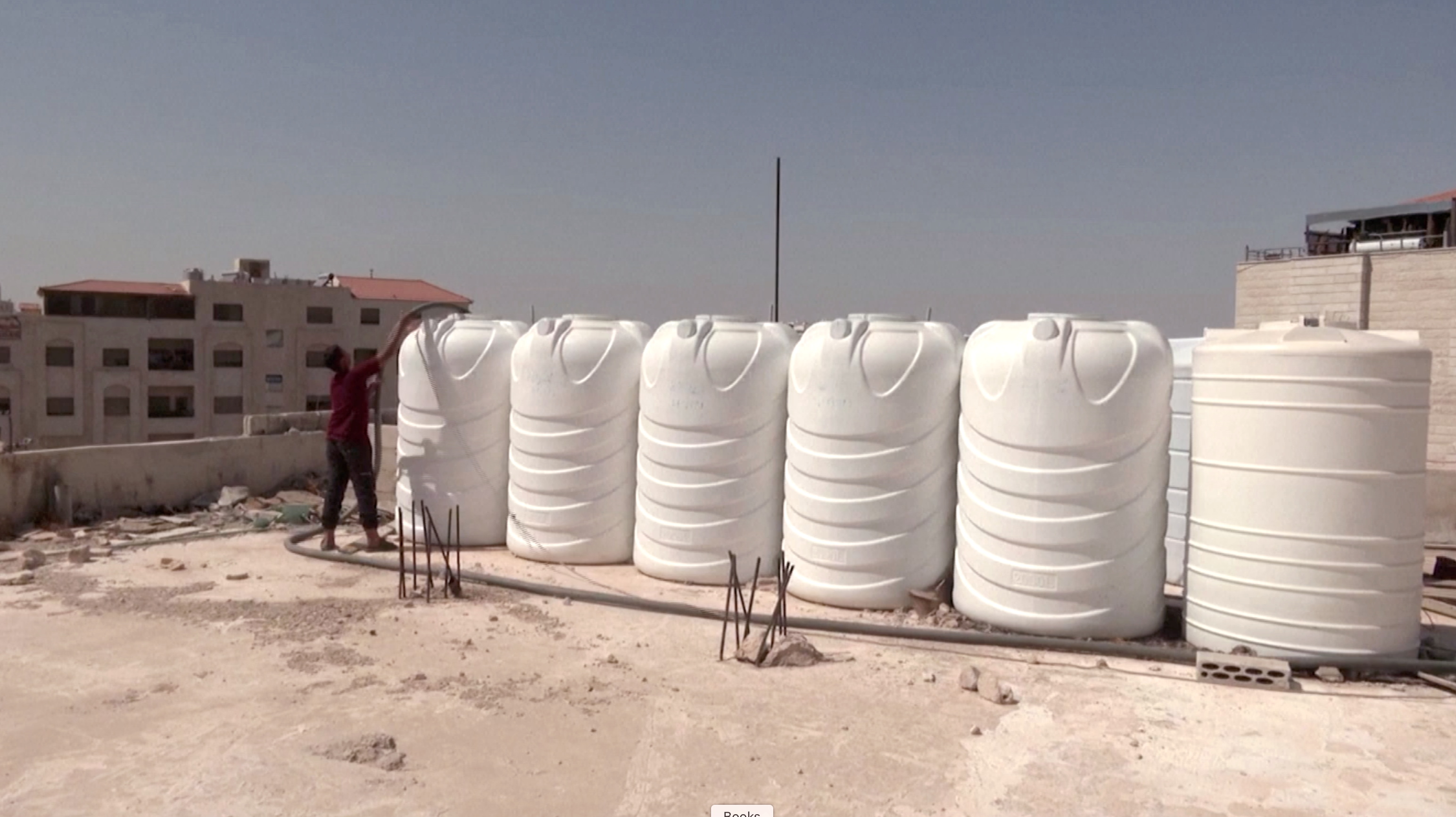 A screen grab shows a boy as he fills tanks with water, in Amman