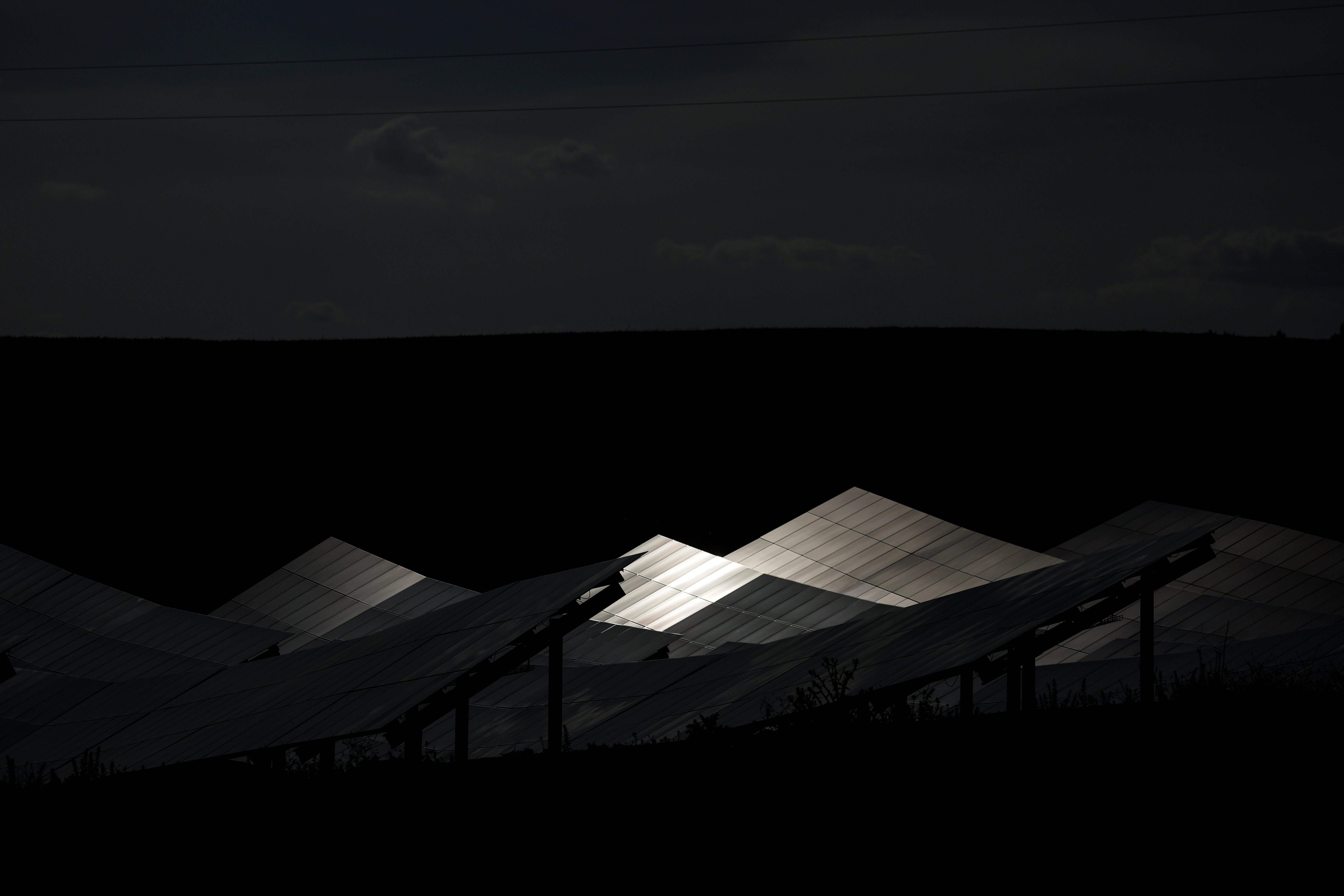 The sun bathes an array of solar panels at a solar energy park in Saelices