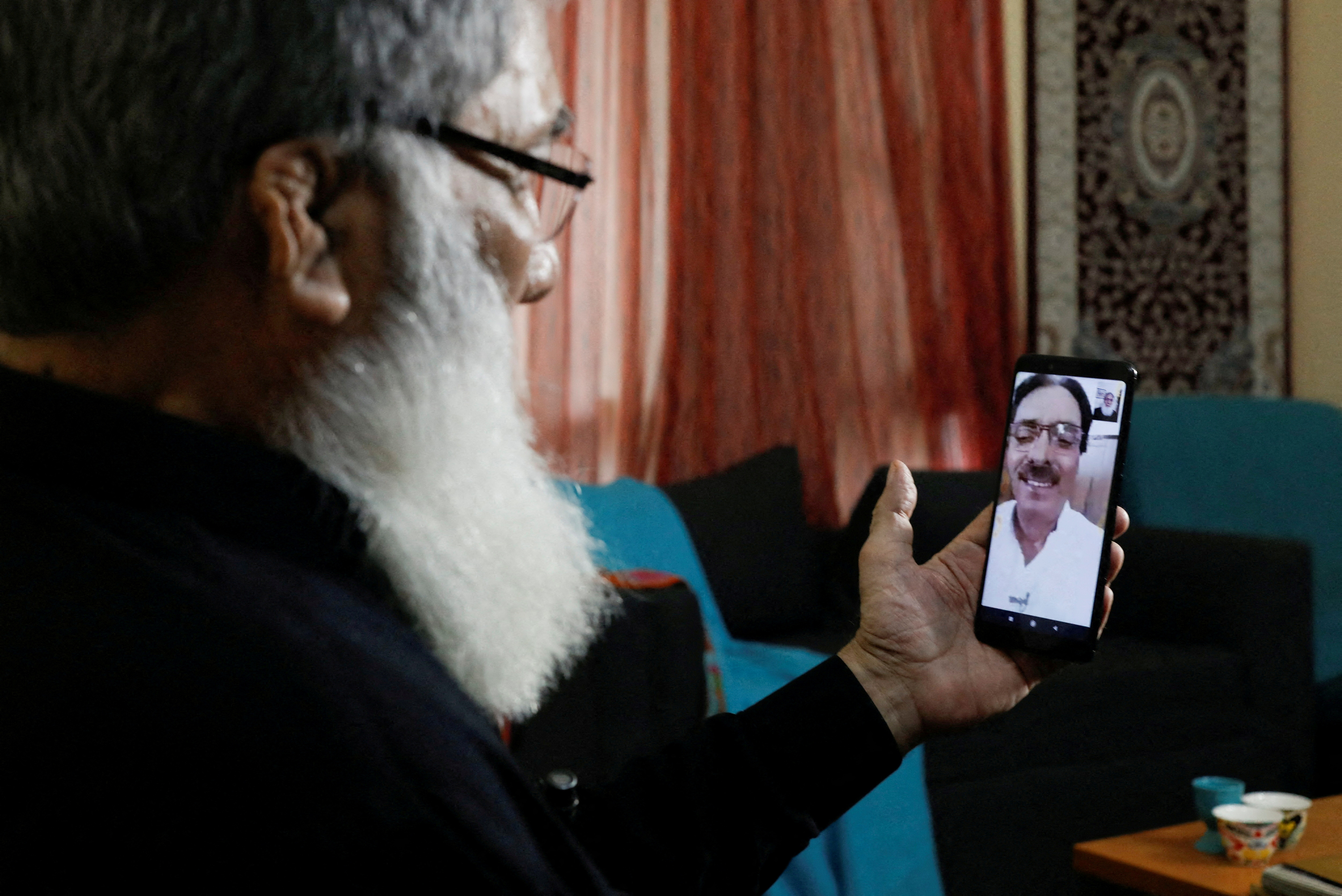 Ali Hasan Baqai, speaks on a video call, with his Indian citizen brother Abid Hasan Baqai, at his home in Karachi