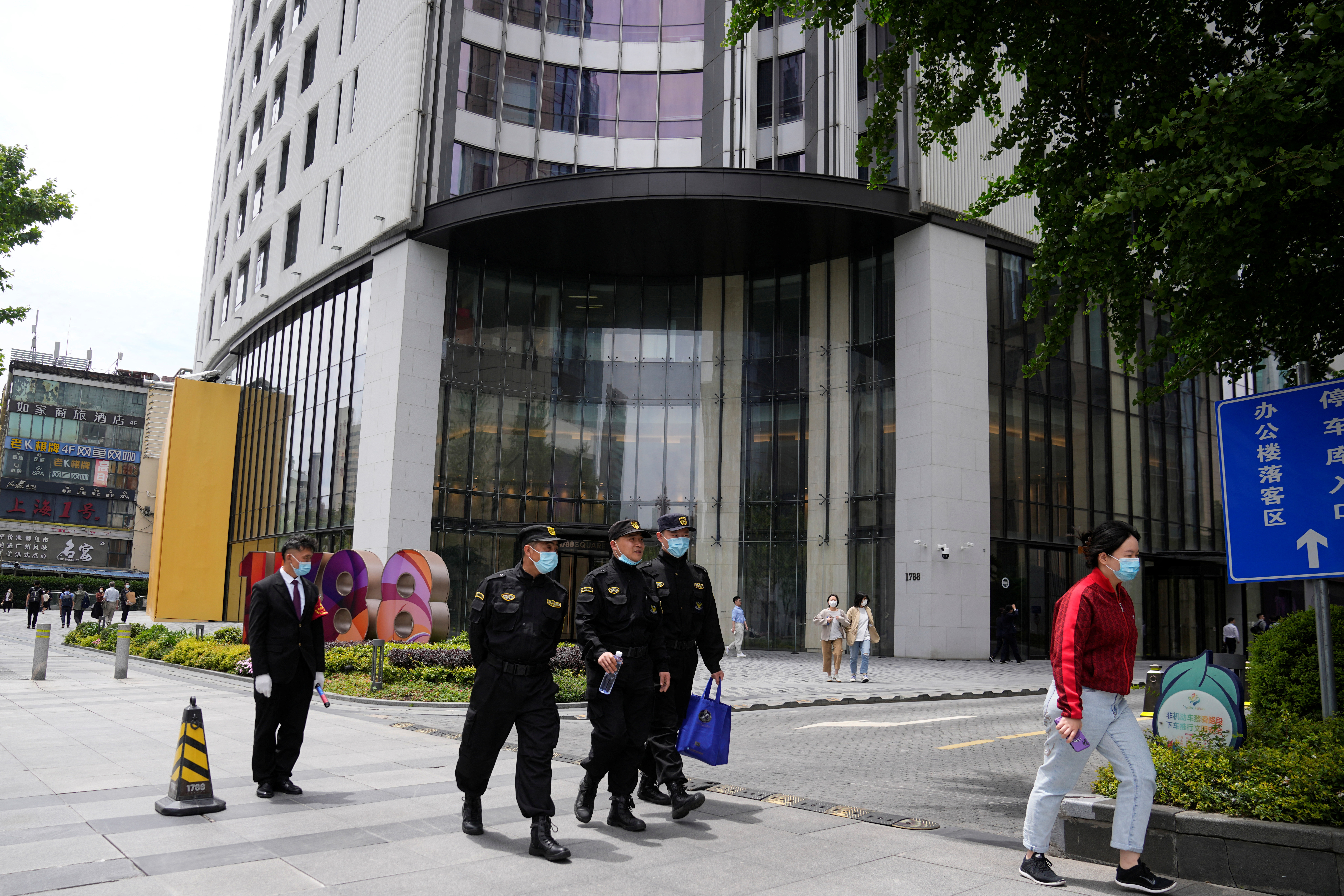 Le guardie di sicurezza passano davanti a un edificio per uffici, dove si trovano le strutture del consolato generale canadese, a Shanghai