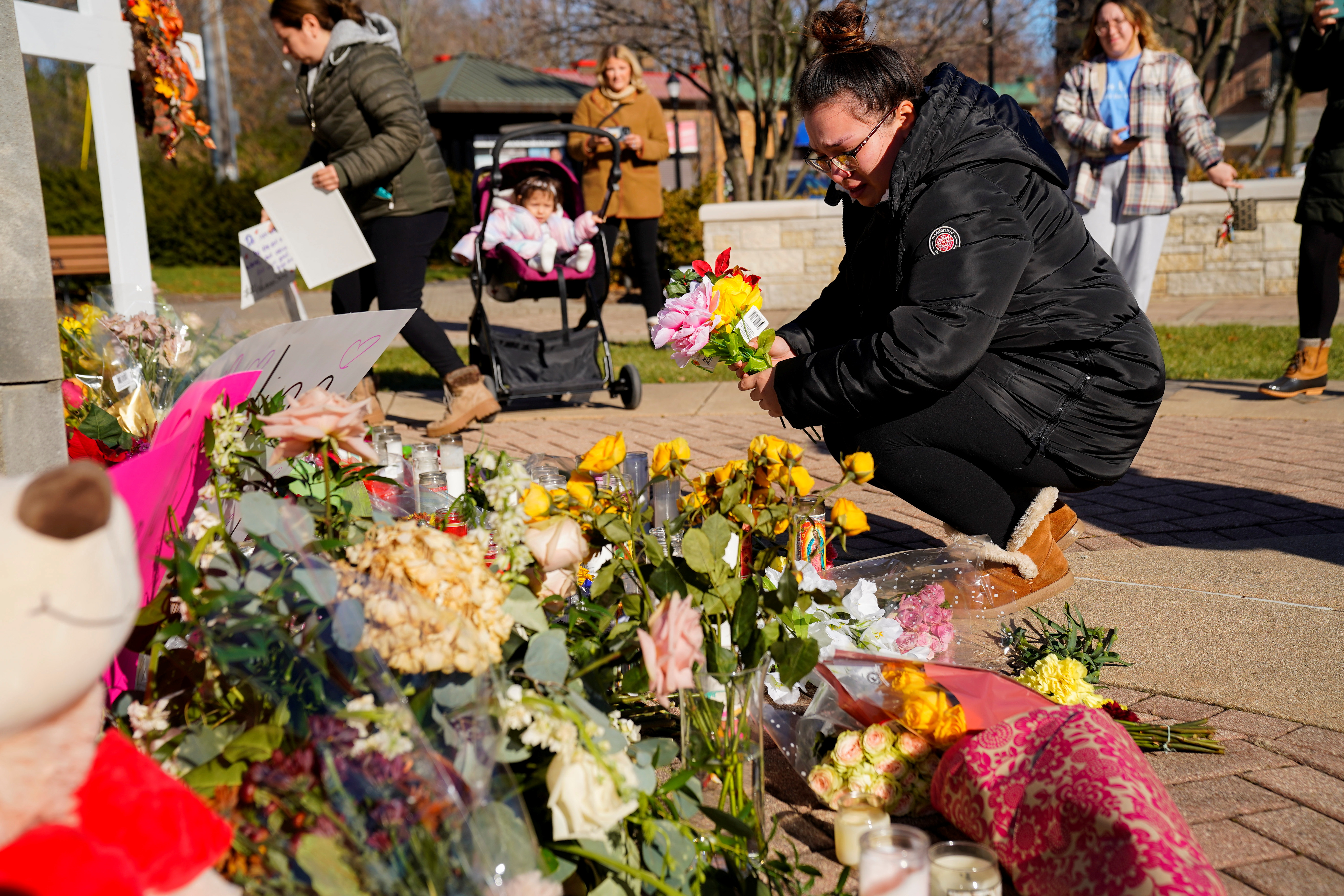 Alexandera Cimbalnik, 20, lays flowers at a memorial at Veterans Park after a car plowed through a holiday parade in Waukesha, Wisconsin, U.S., November 23, 2021.  REUTERS/Cheney Orr
