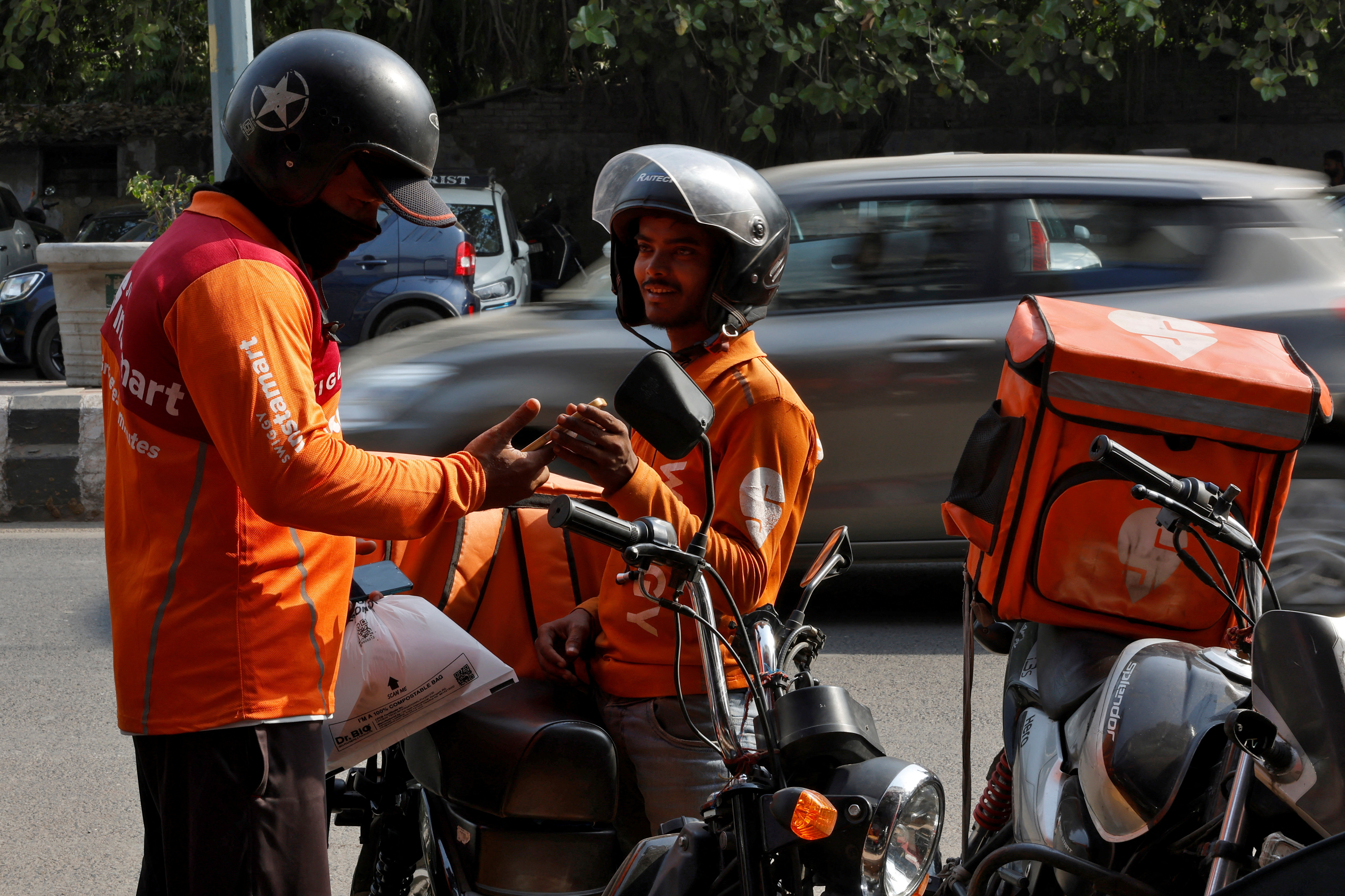Gig workers prepare to deliver orders outside Swiggy's grocery warehouse, in New Delhi