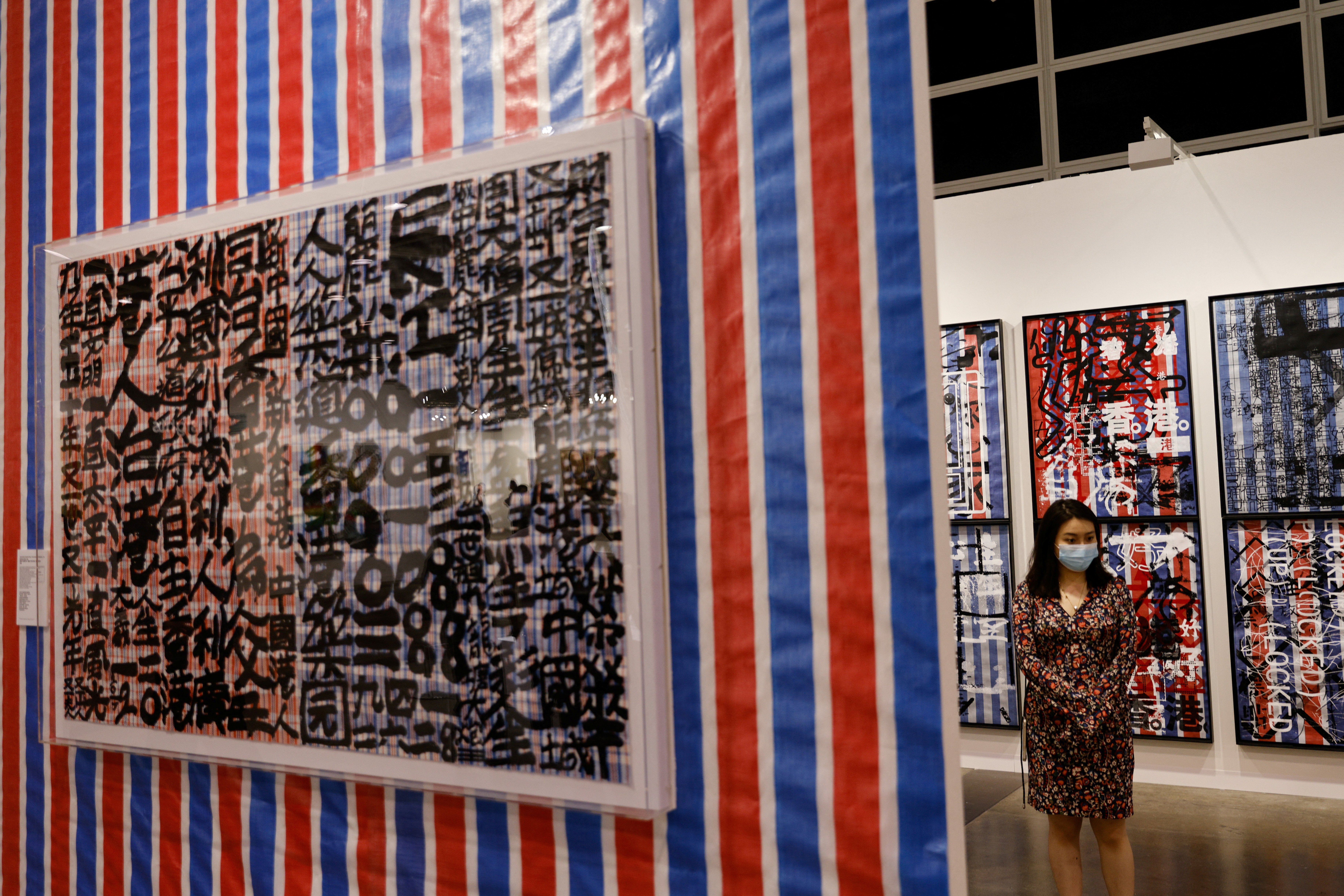 A woman stands next to artworks by Stanley Wong, also know as 