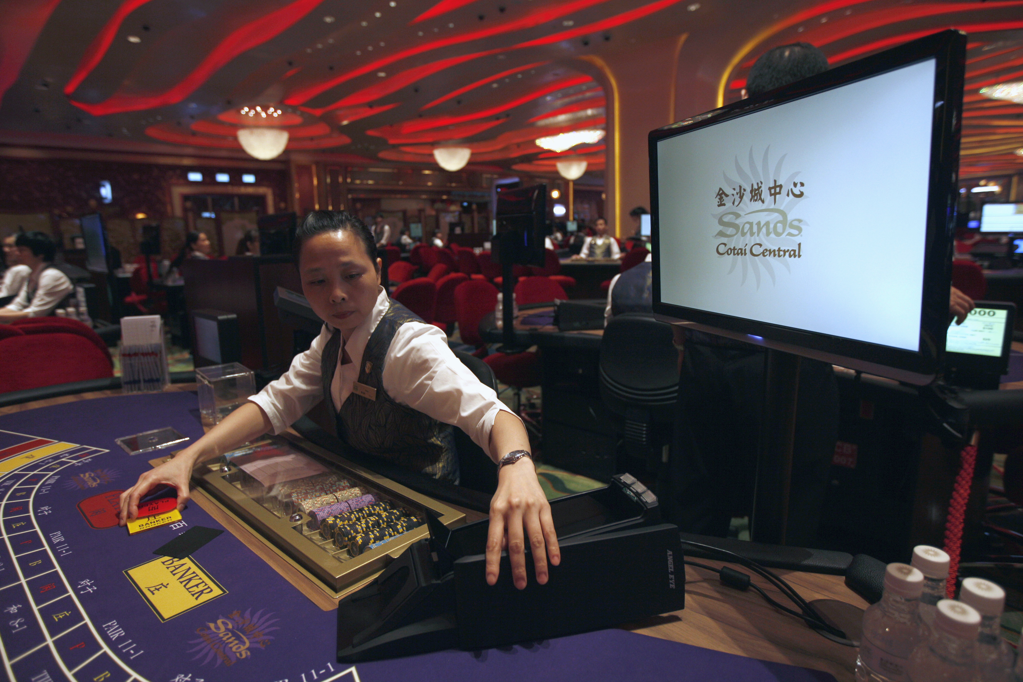 A croupier reacts in front of a gaming table inside a casino on the opening day of Sheraton Macao hotel in Sands Cotai Central in Macau