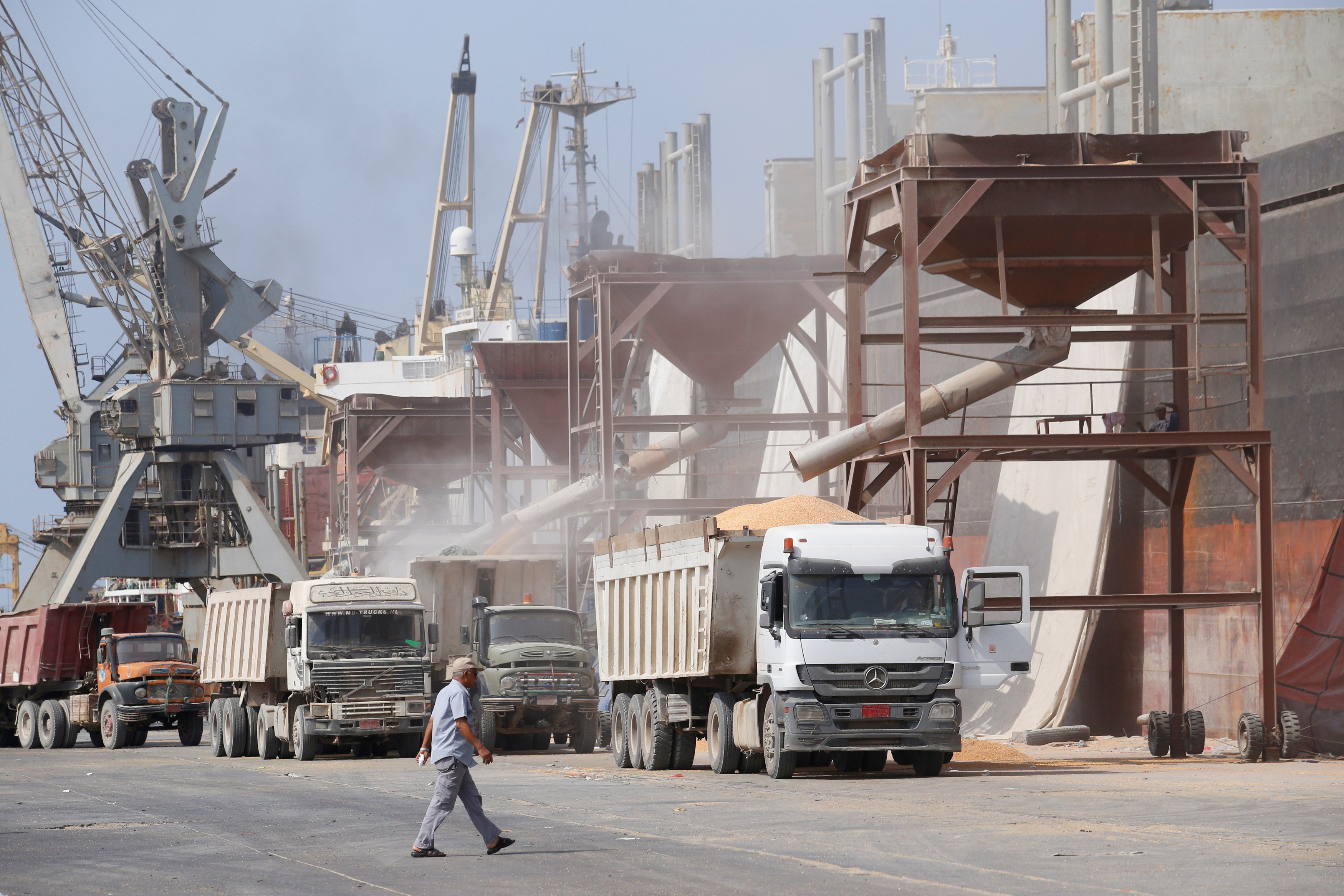 Man walks past a cargo ship unloading wheat at the Red Sea port of Hodeida, Yemen