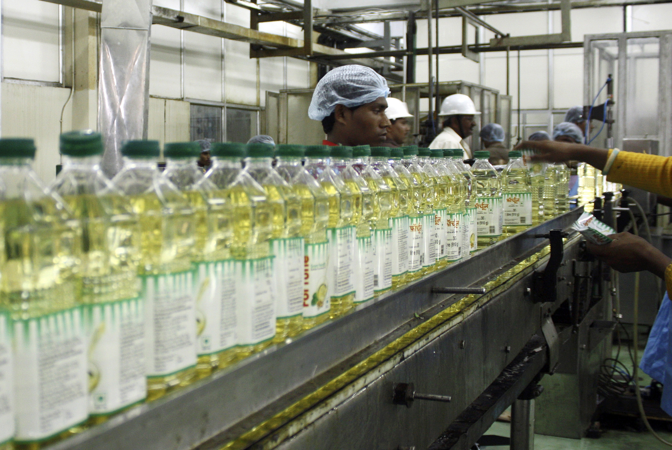 Employees fill plastic bottles with edible oil at an oil refinery plant of Adani Wilmar Ltd in Mundra
