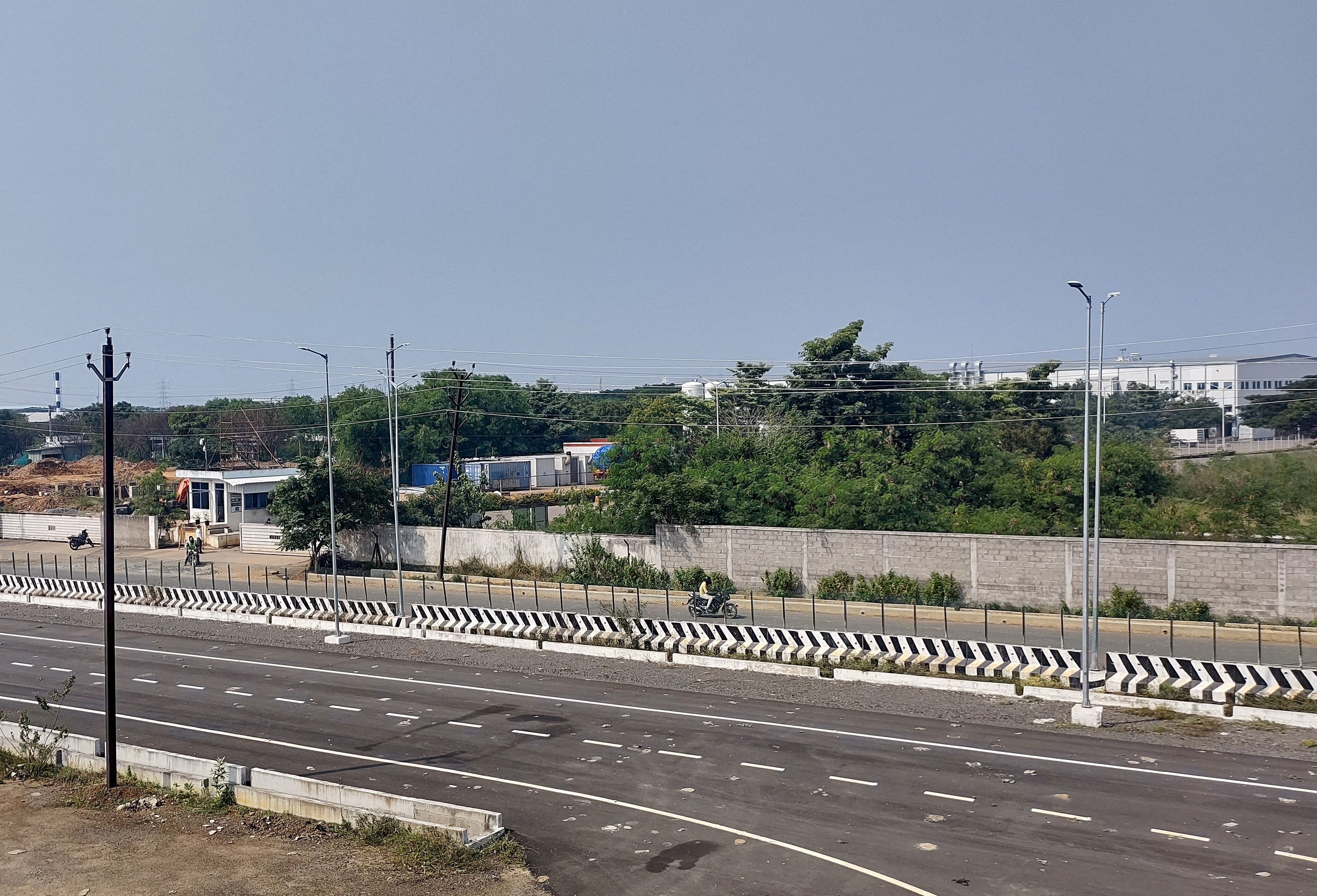 Men ride their motorbikes past a closed plant of India Foxconn unit, near Chennai