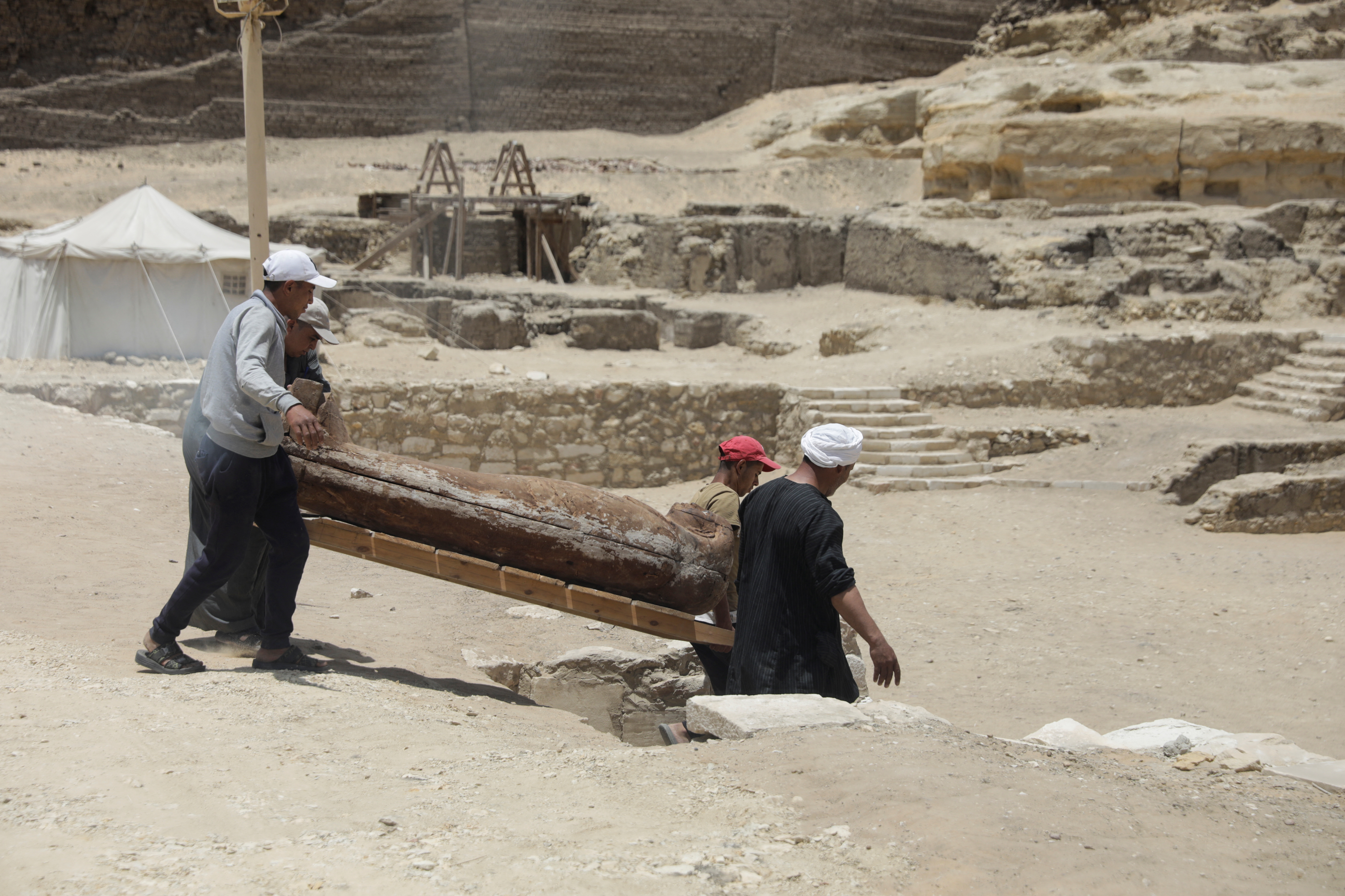Workers carry a sarcophagus from newly discovered burial site, in Giza