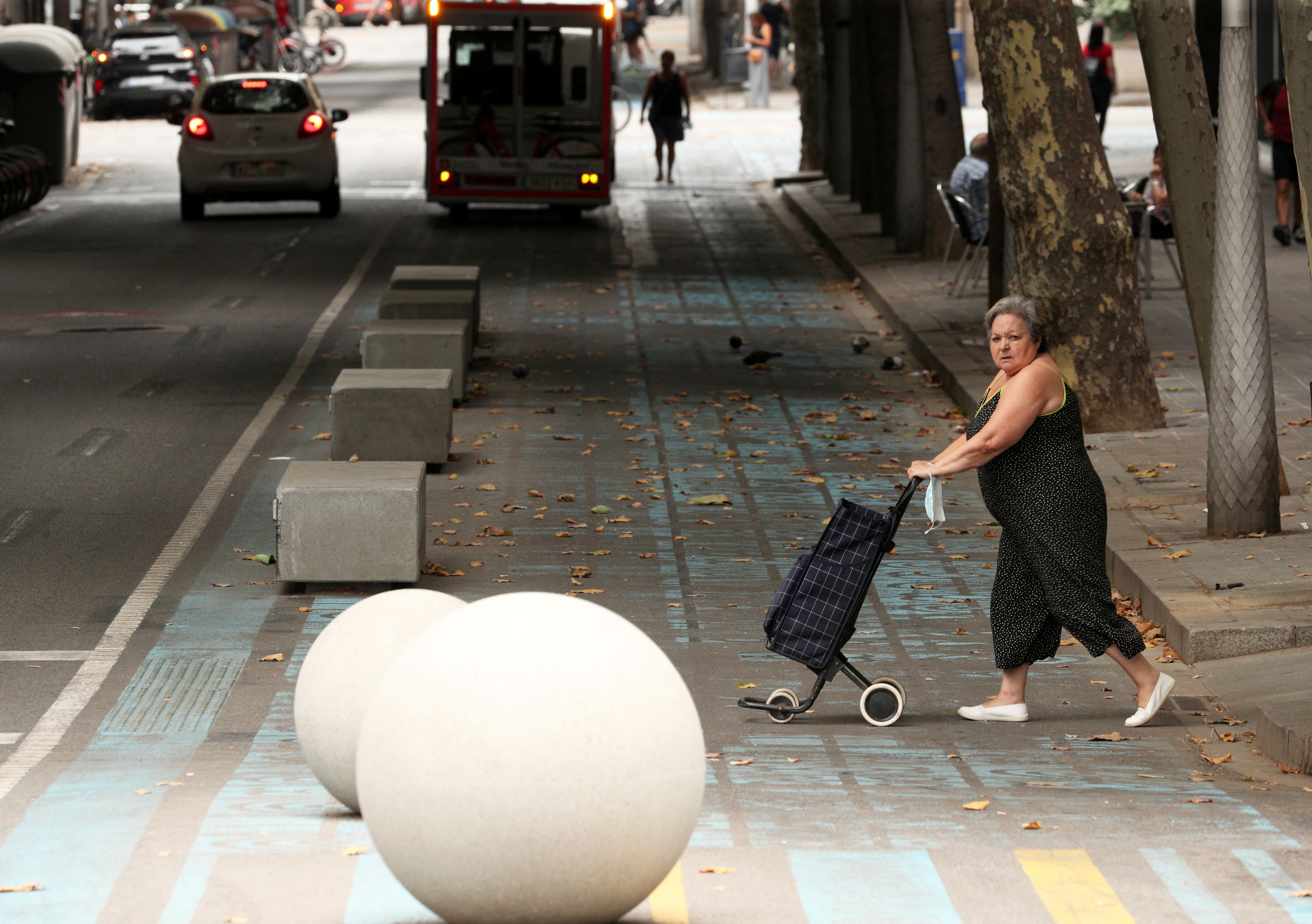 Woman walks by a pedestrian zone painted in blue and yellow at a junction in Barcelona