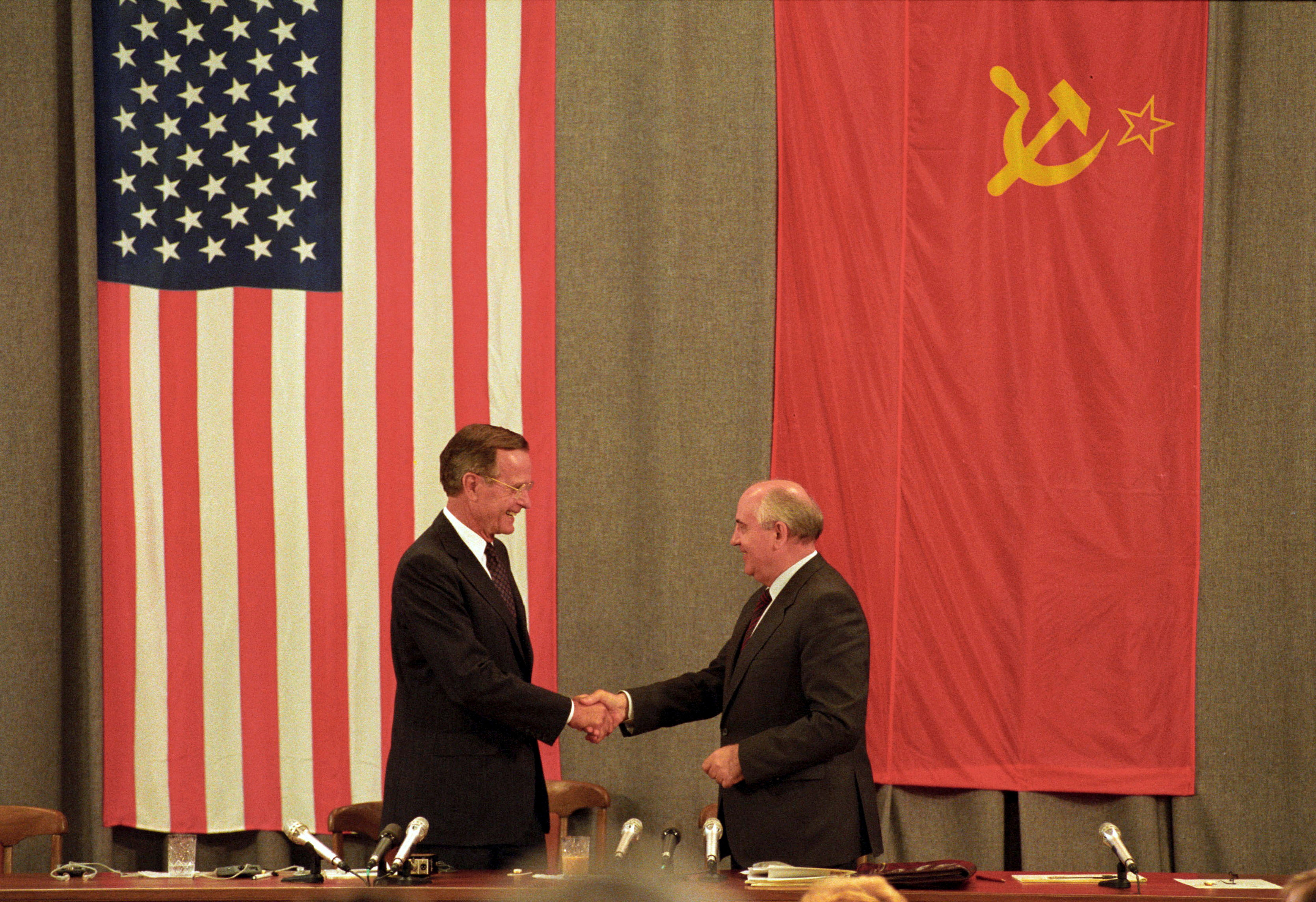 U.S. President George H. W. Bush (L) and Soviet President Mikhail Gorbachev shake hands in front of U.S. and Soviet flags at the end of the press conference in Moscow