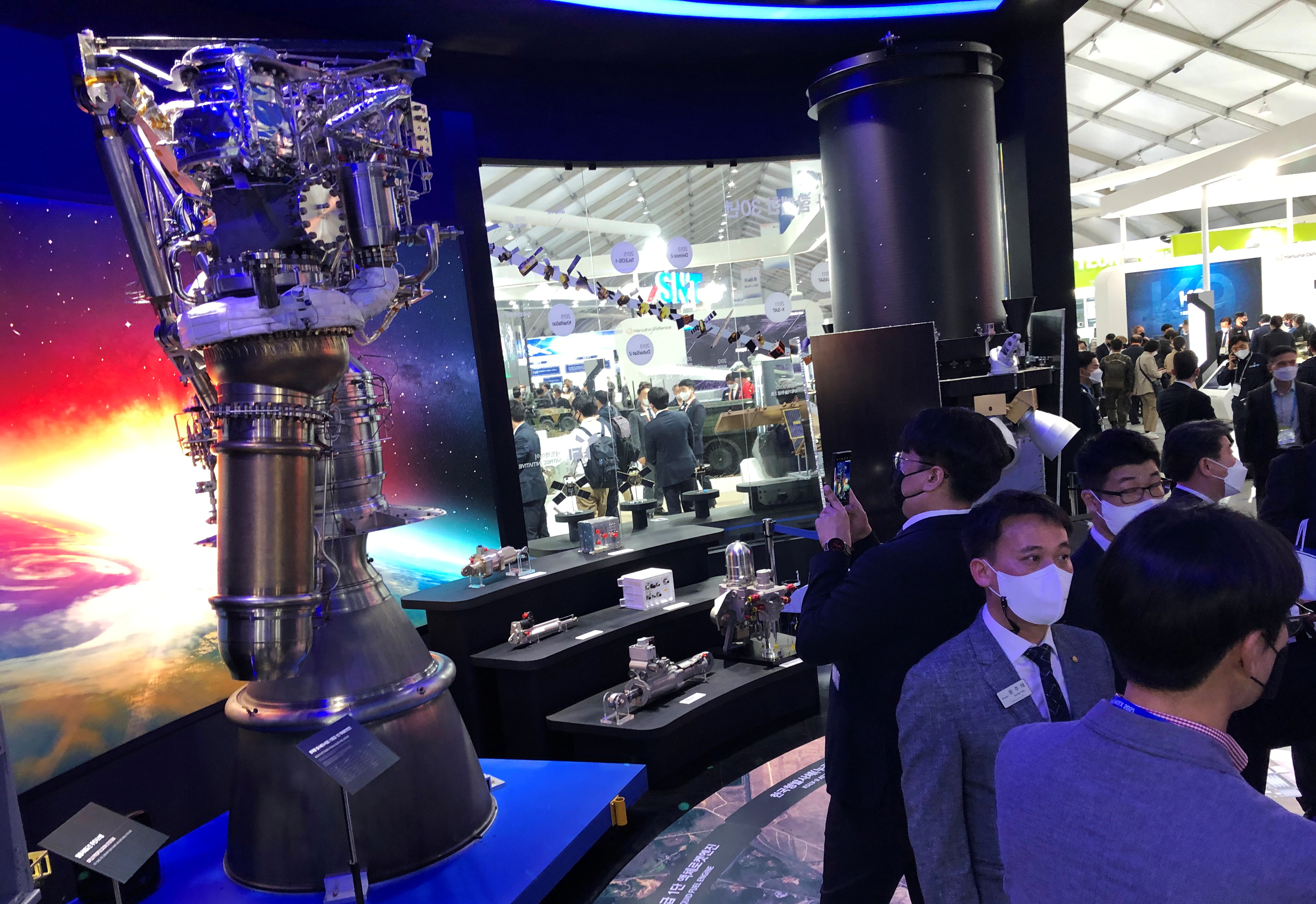 Participants looks at a display of rocket engines and other components manufactured by Hanwha during the Seoul International Aerospace and Defense Exhibition, in Seongnam