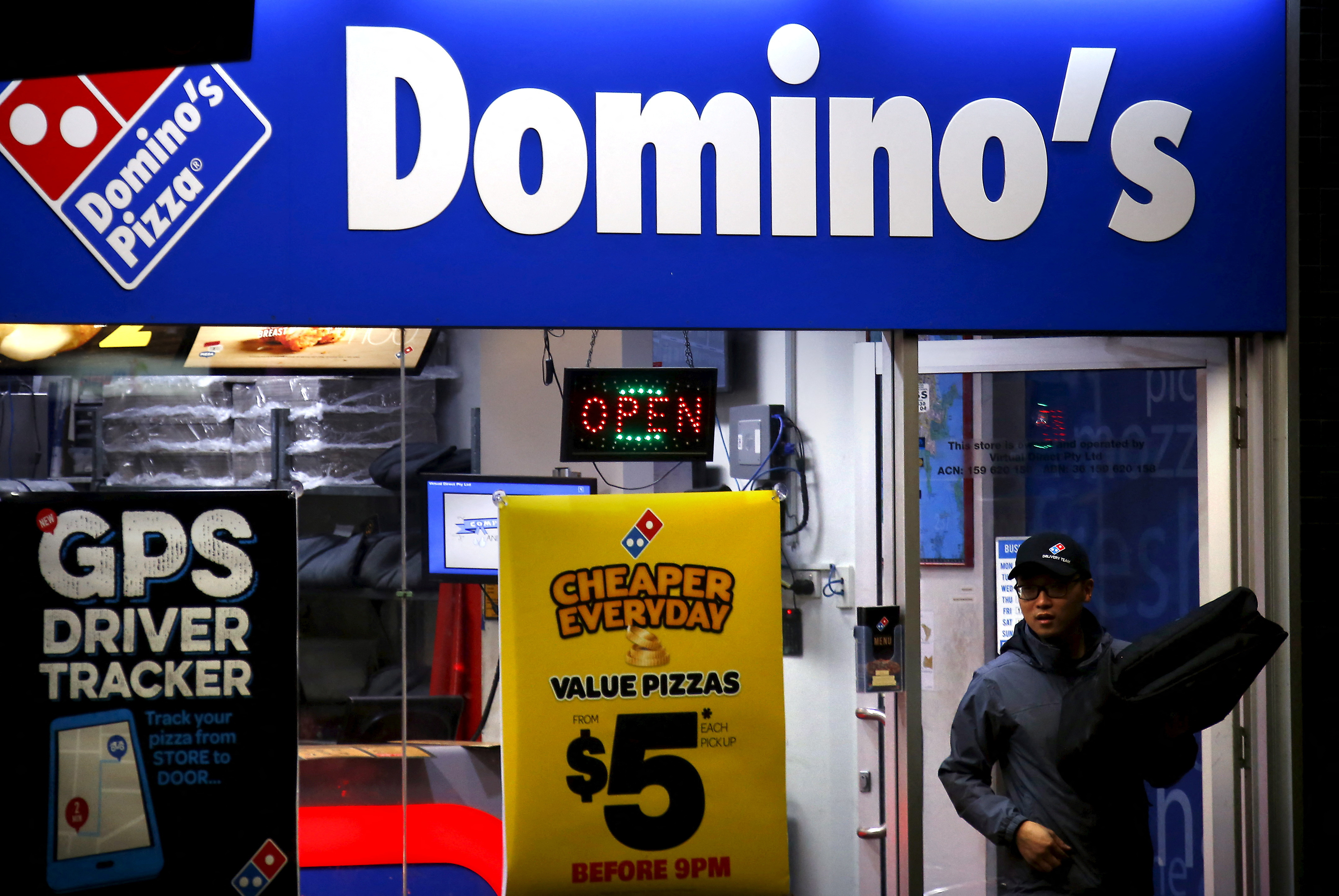 A worker carries a pizza for delivery as he exits a Domino's pizza store in Sydney, Australia