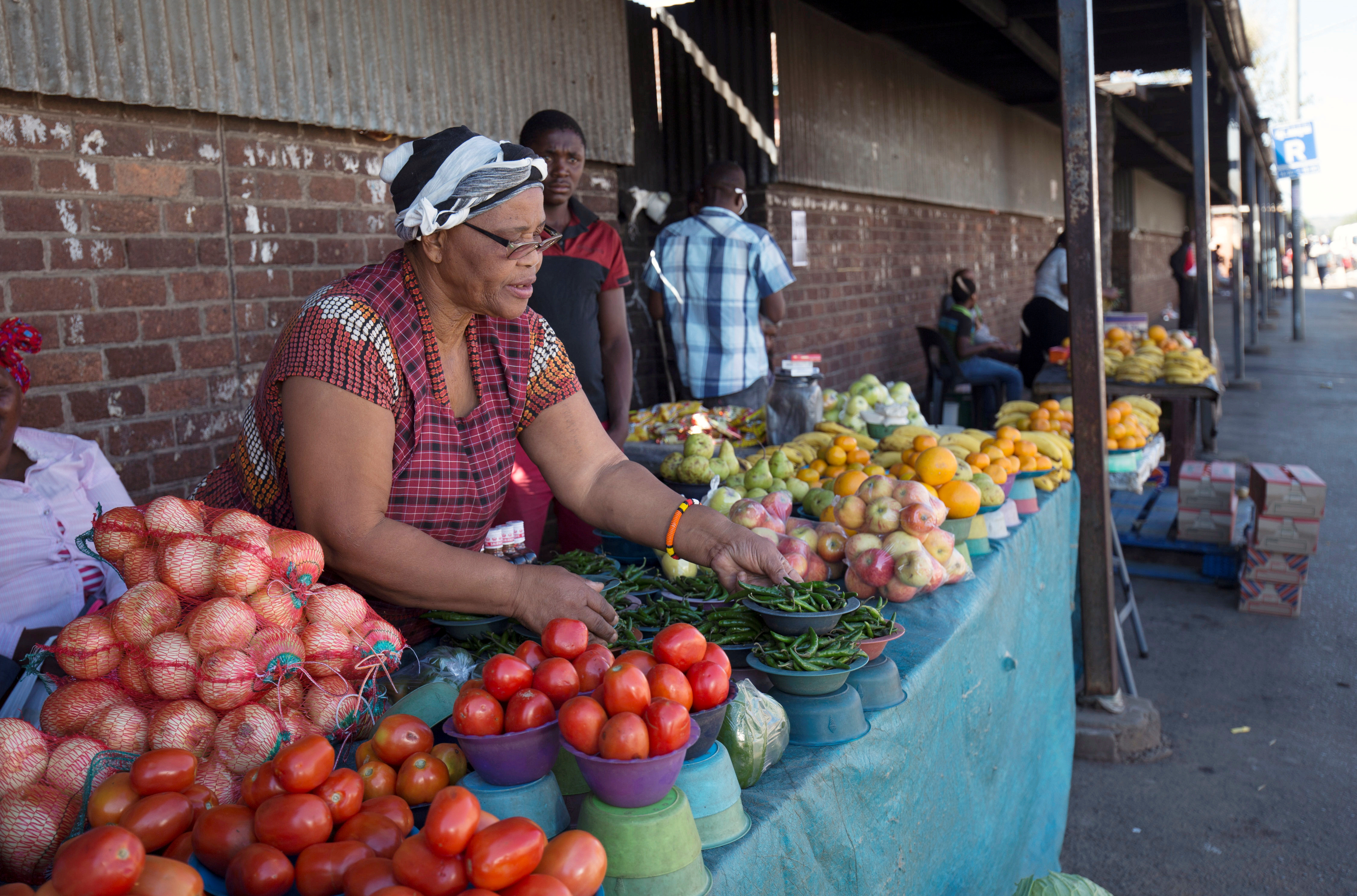 A street trader arranges fresh vegetables and fruit on a street in Pietermaritzburg