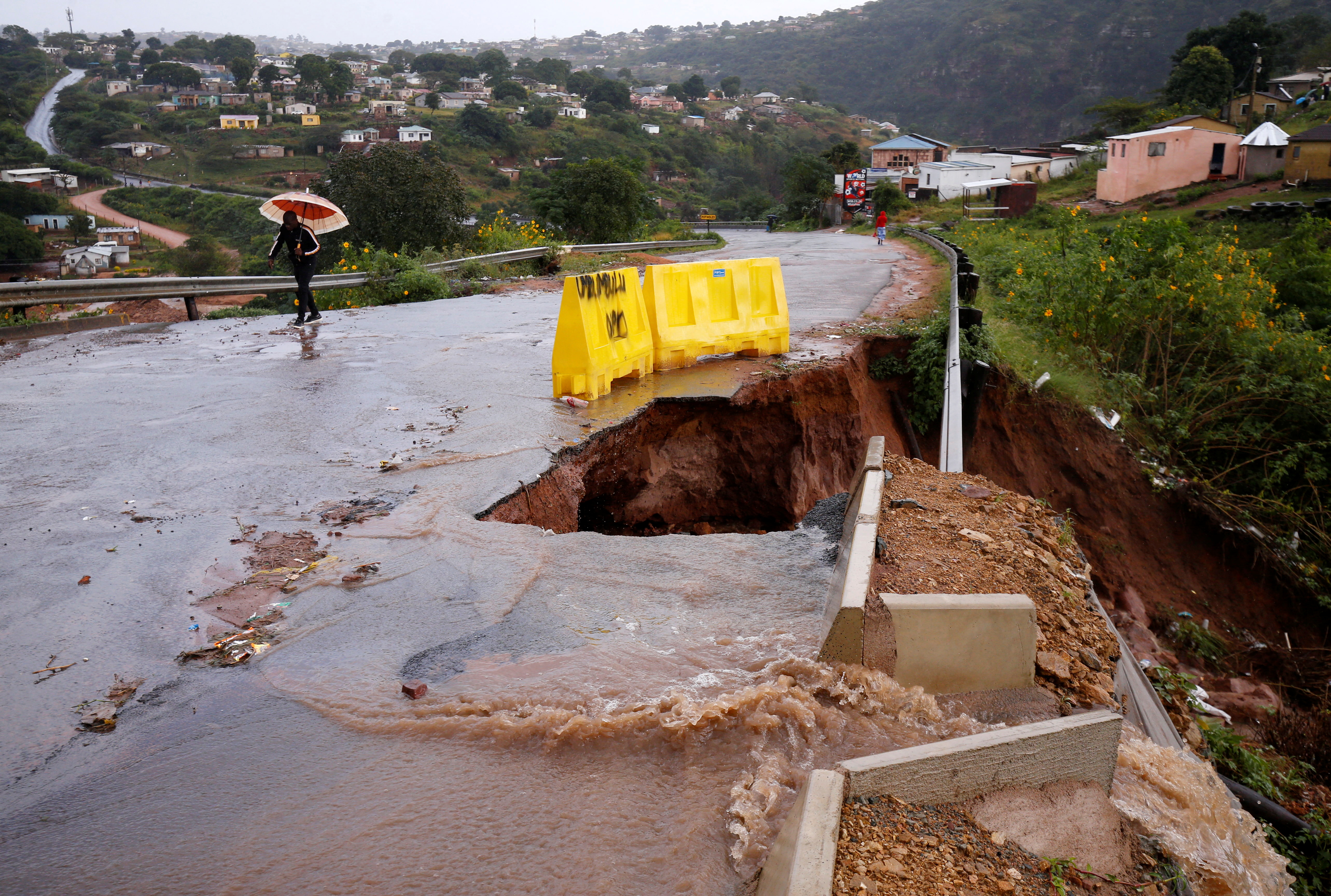 Water from heavy rains runs along a road, which was damaged during previous flooding, in kwaNdengezi