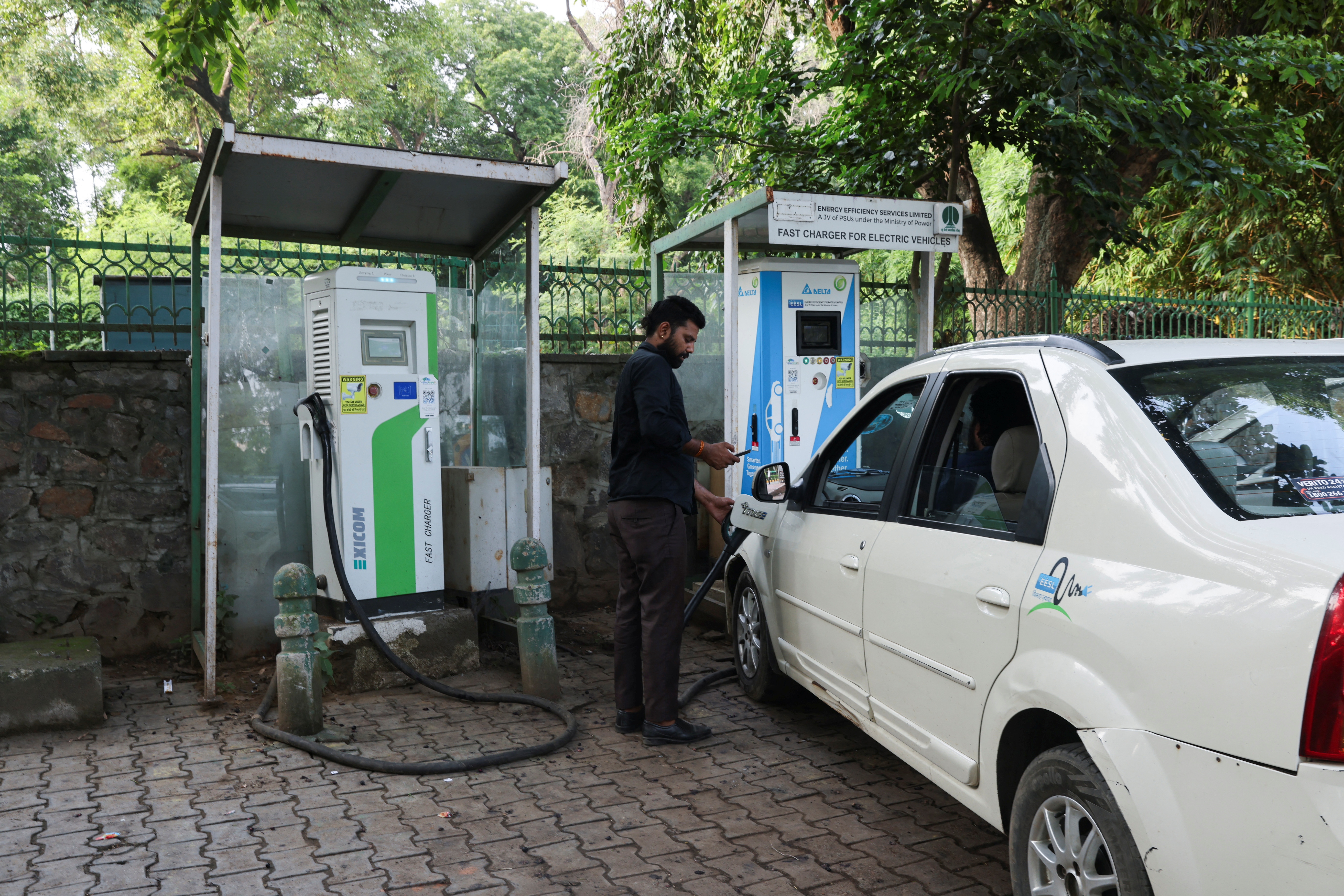 A man plugs an electric car at a charging station in New Delhi
