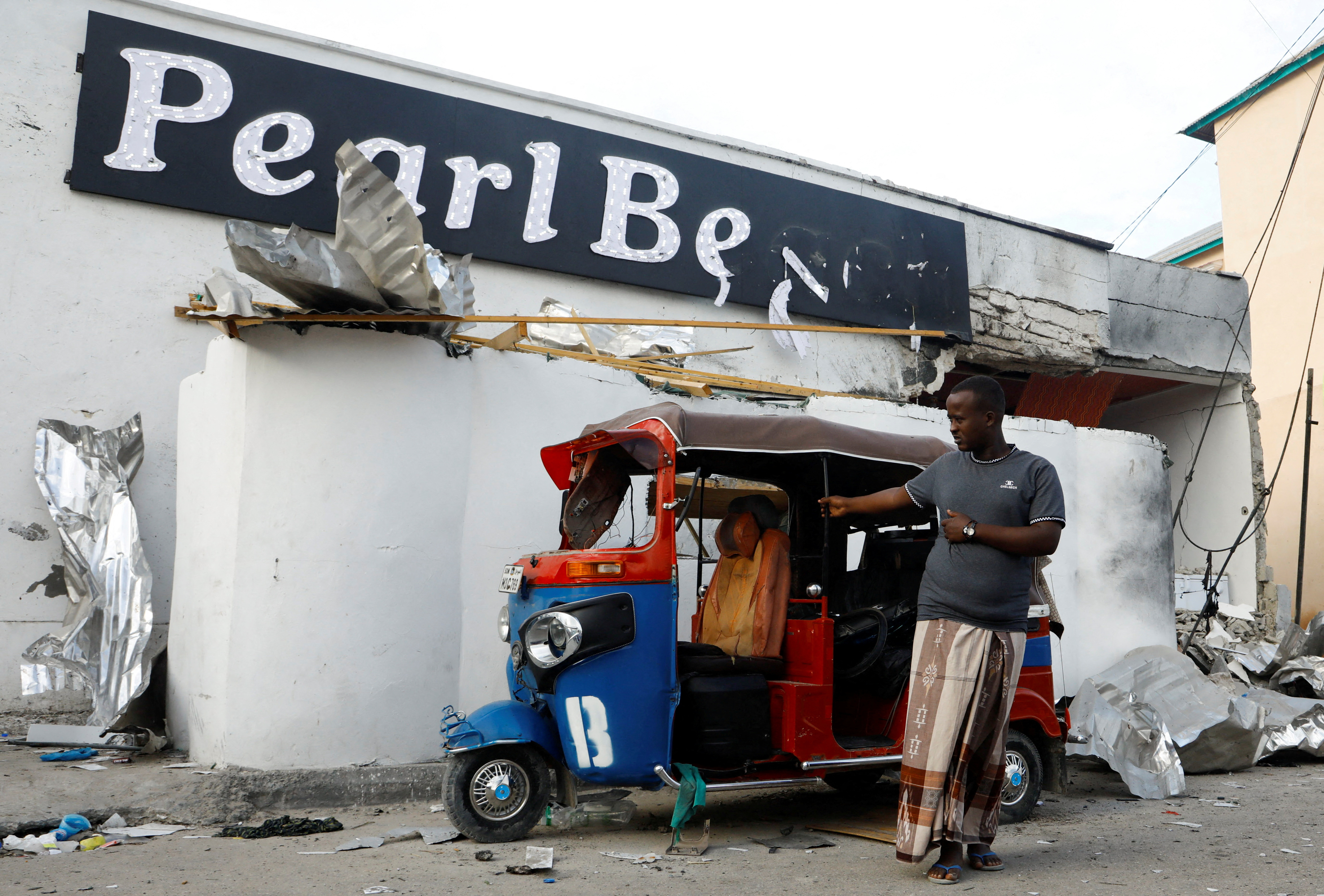 A driver looks at the wreckage of a rickshaw destroyed during an attack by Al Shabaab militants in front of the Pearl beach restaurant at Liido beach in Mogadishu