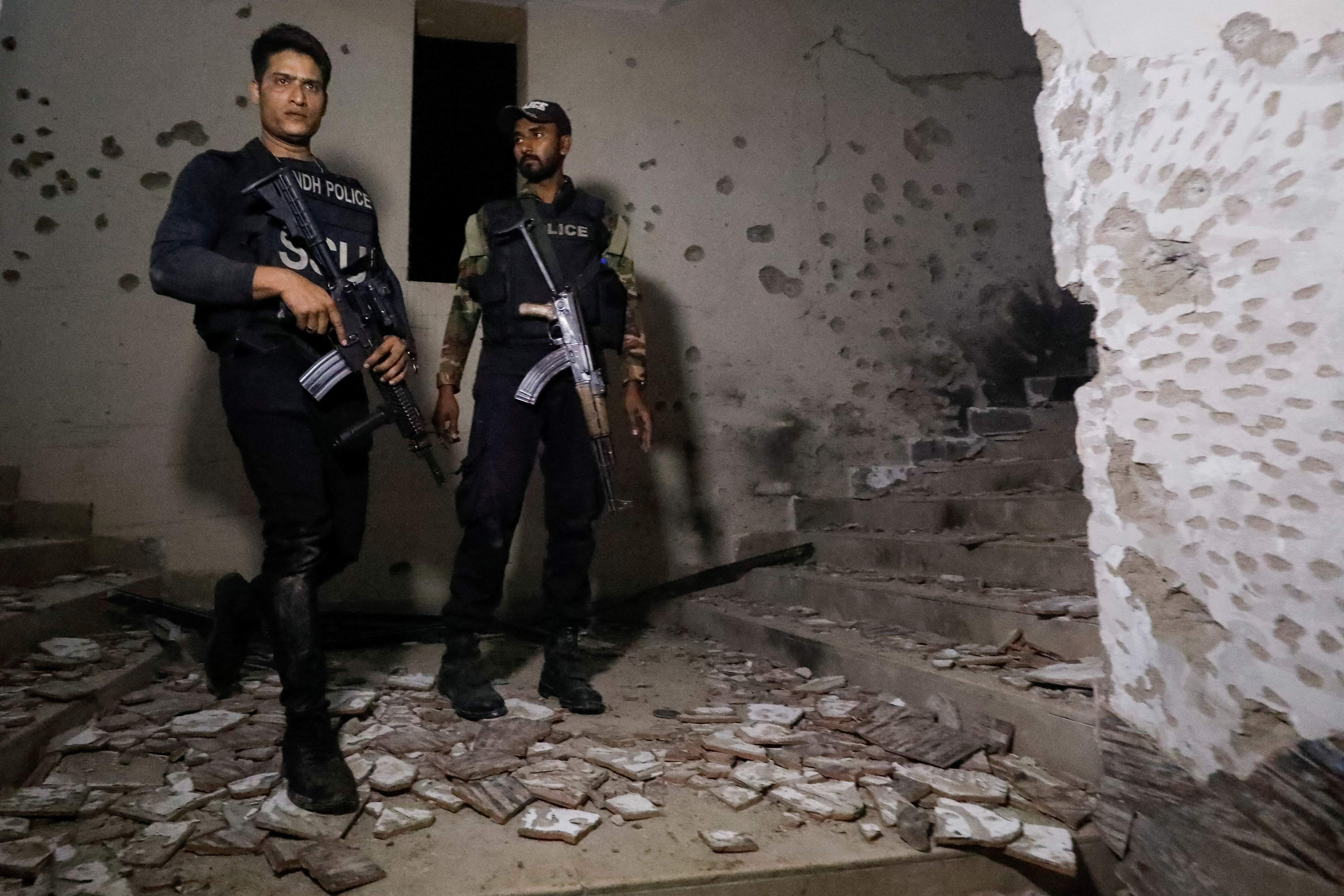 Police officers stand in the aftermath of an attack on a police station in Karachi