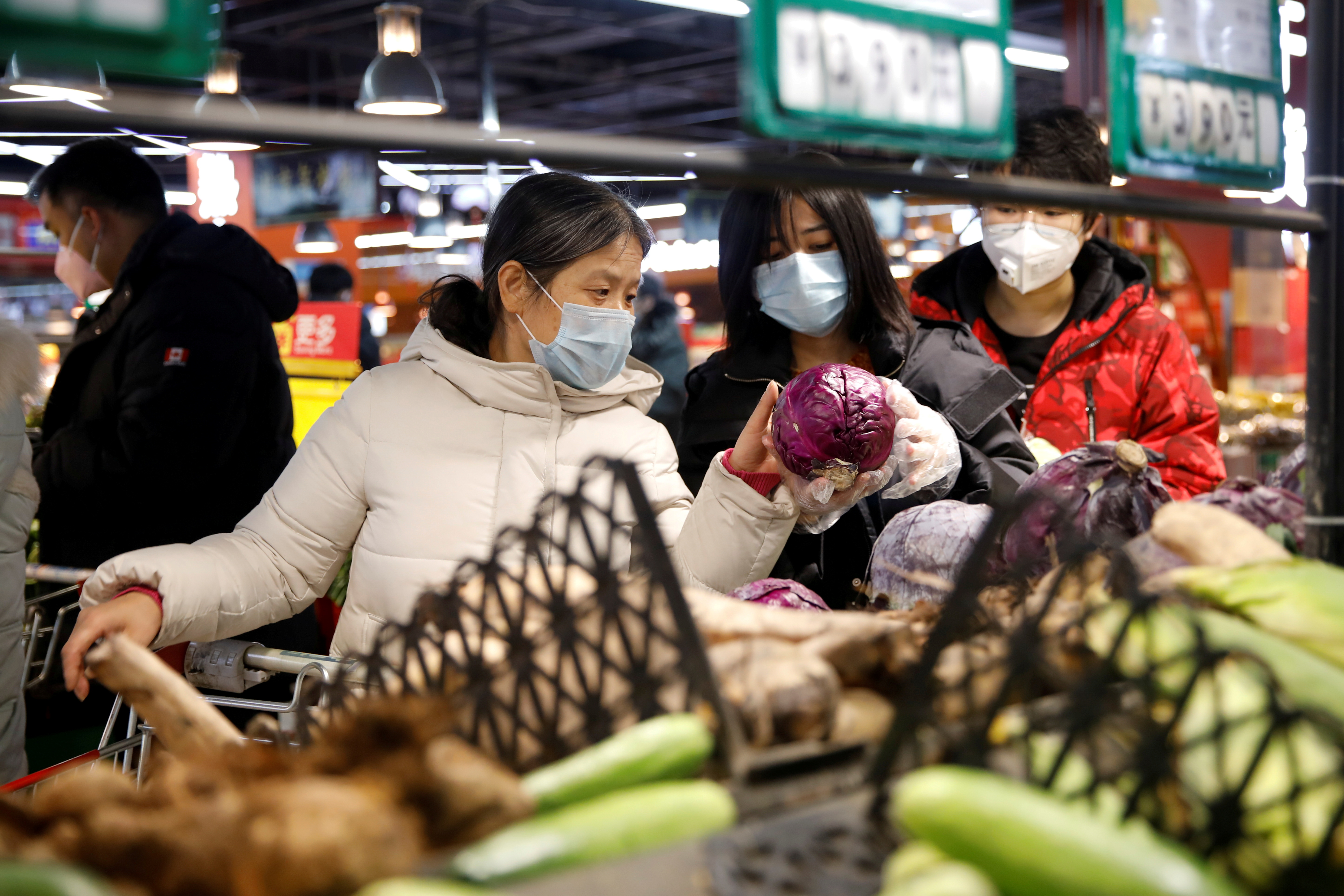 People wearing face masks look for products at a supermarket in Beijing