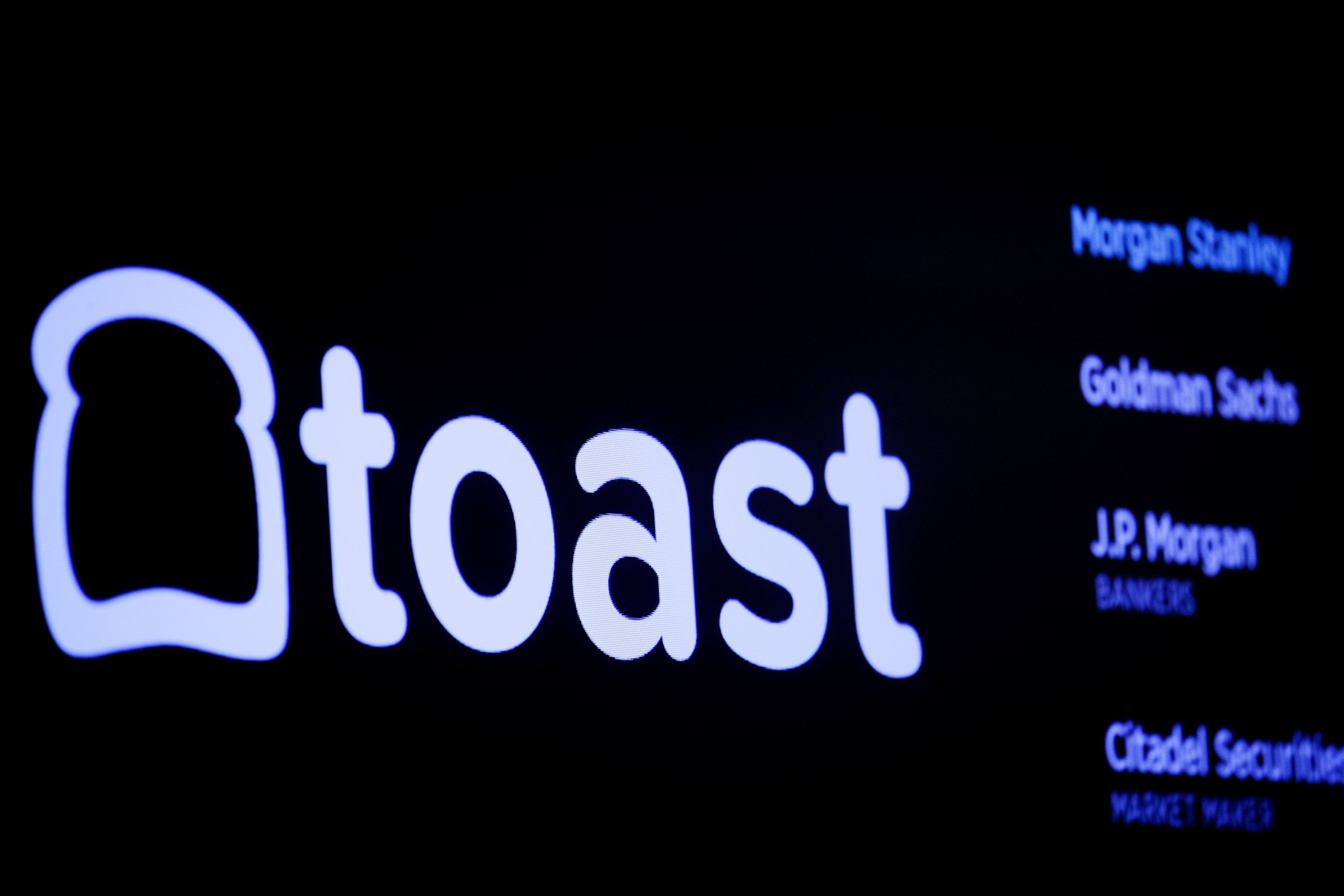 A screen displays the company logo for Toast Inc. during the company’s IPO at the NYSE in New York