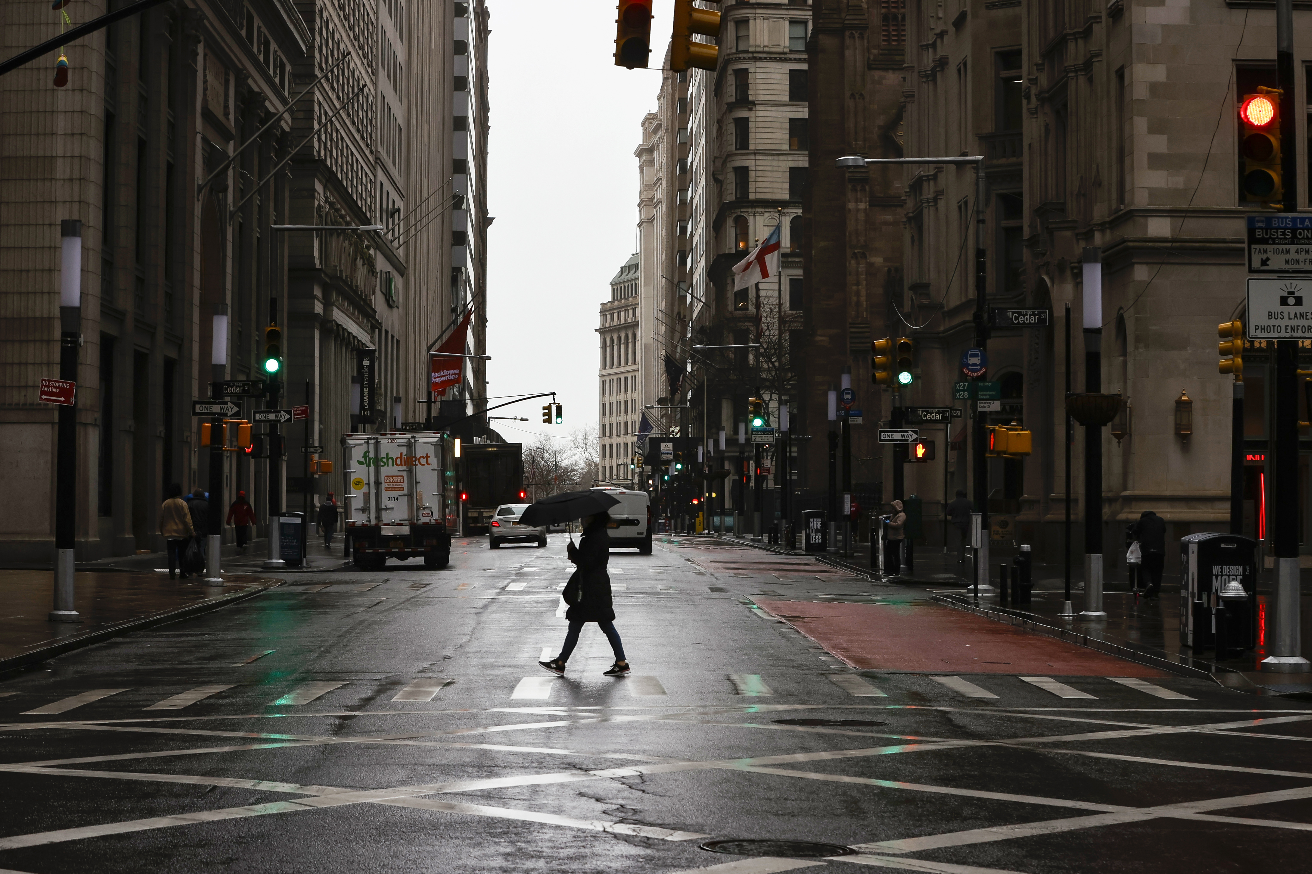 A woman is seen crossing a nearly empty Broadway in the financial district, as the coronavirus disease (COVID-19) outbreak continues, in New York