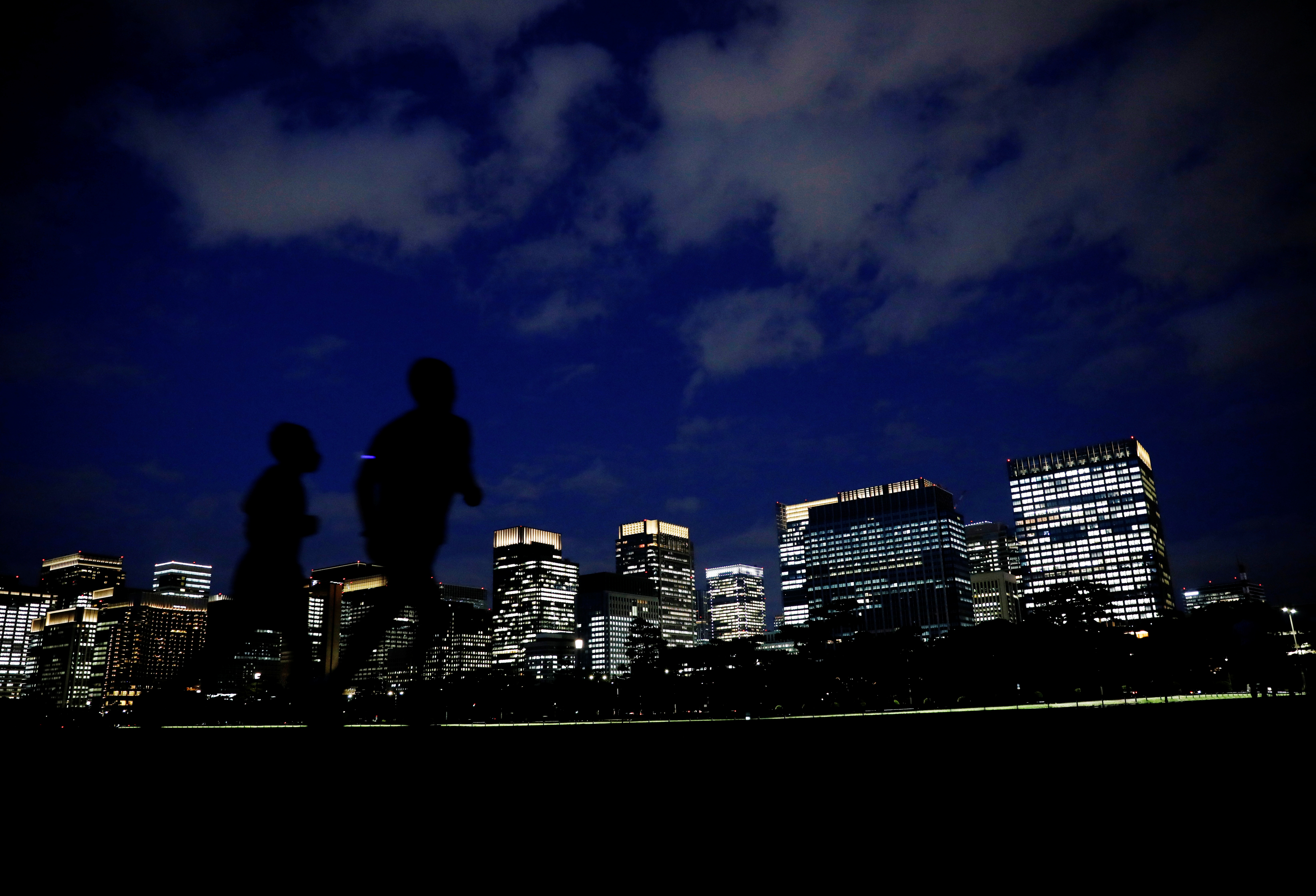 People run with Tokyo's business district in background, in Tokyo
