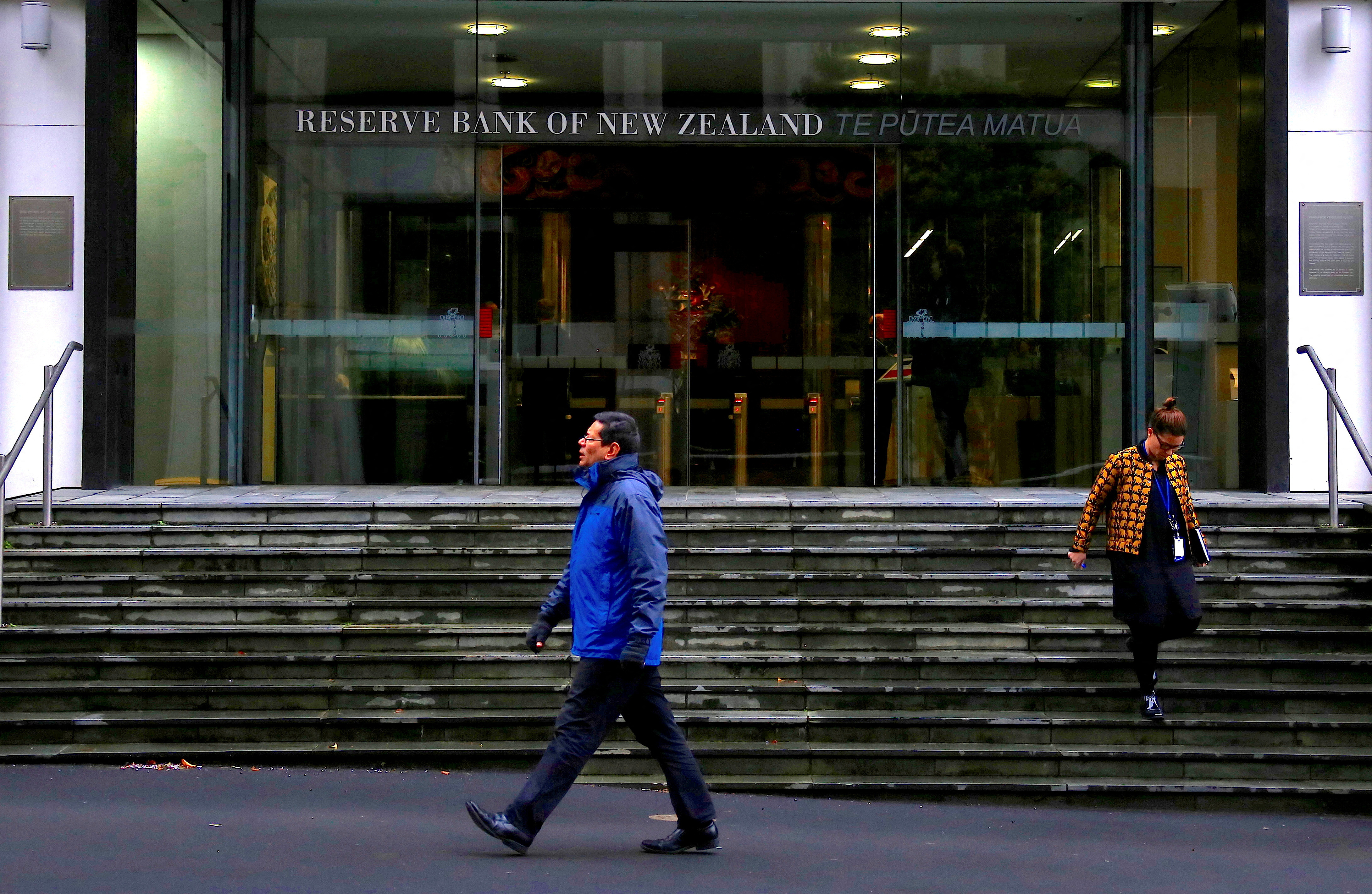 Pedestrians walk near the main entrance to the Reserve Bank of New Zealand located in central Wellington, New Zealand