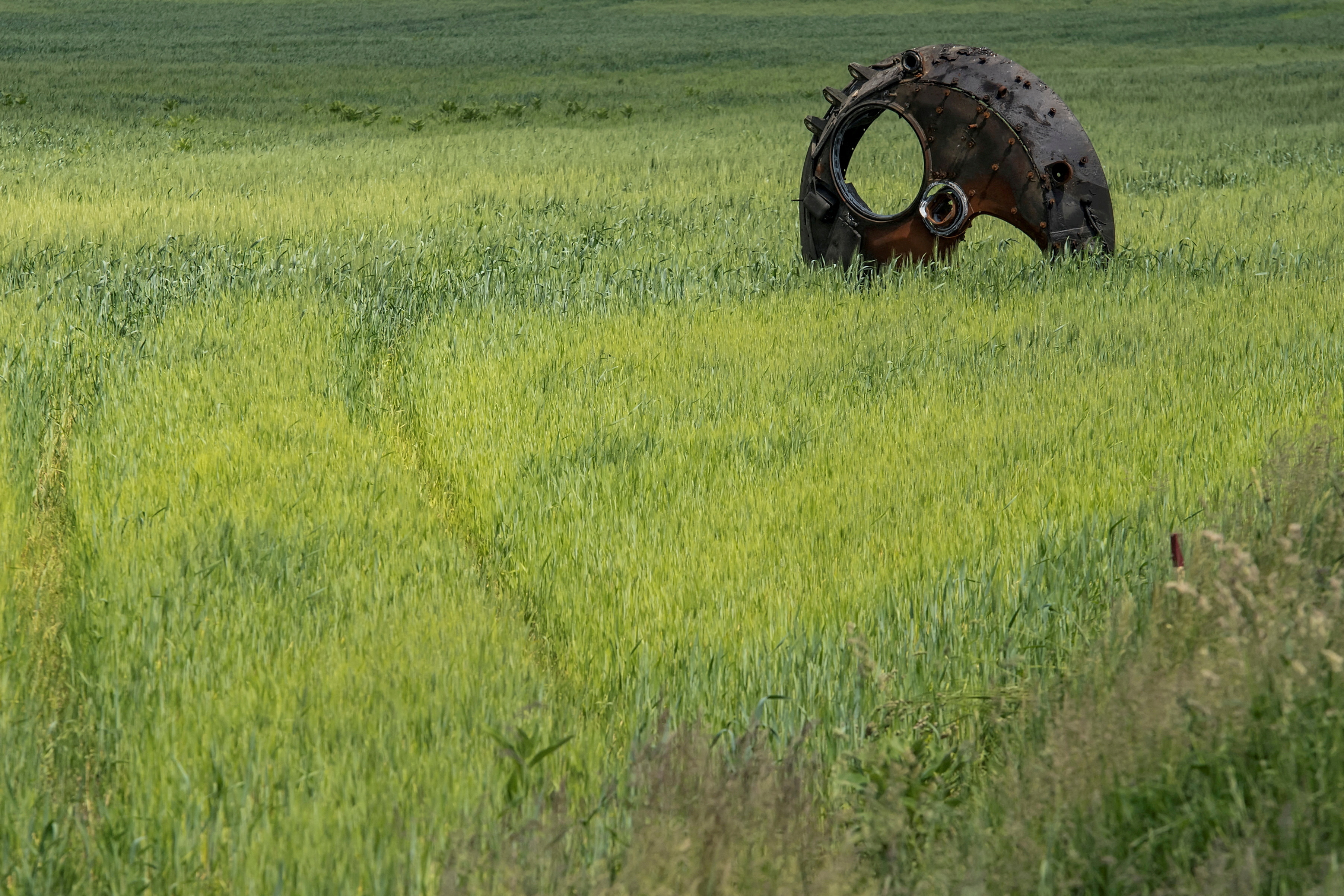 A turret of a destroyed armoured fighting vehicle is seen in a field with wheat outside the town of Ichnia