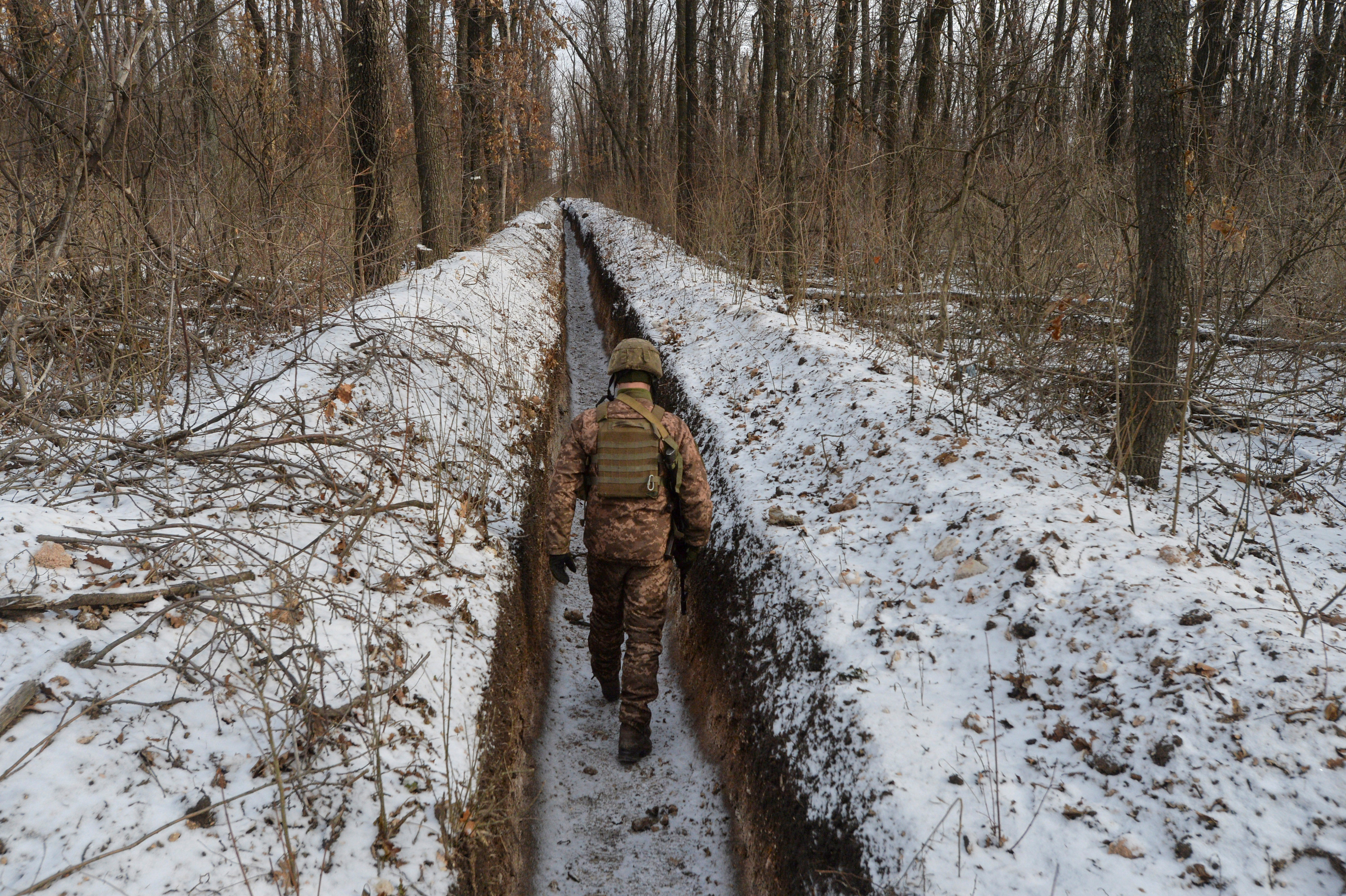 A Ukrainian service member walks along fighting positions near Avdiivka