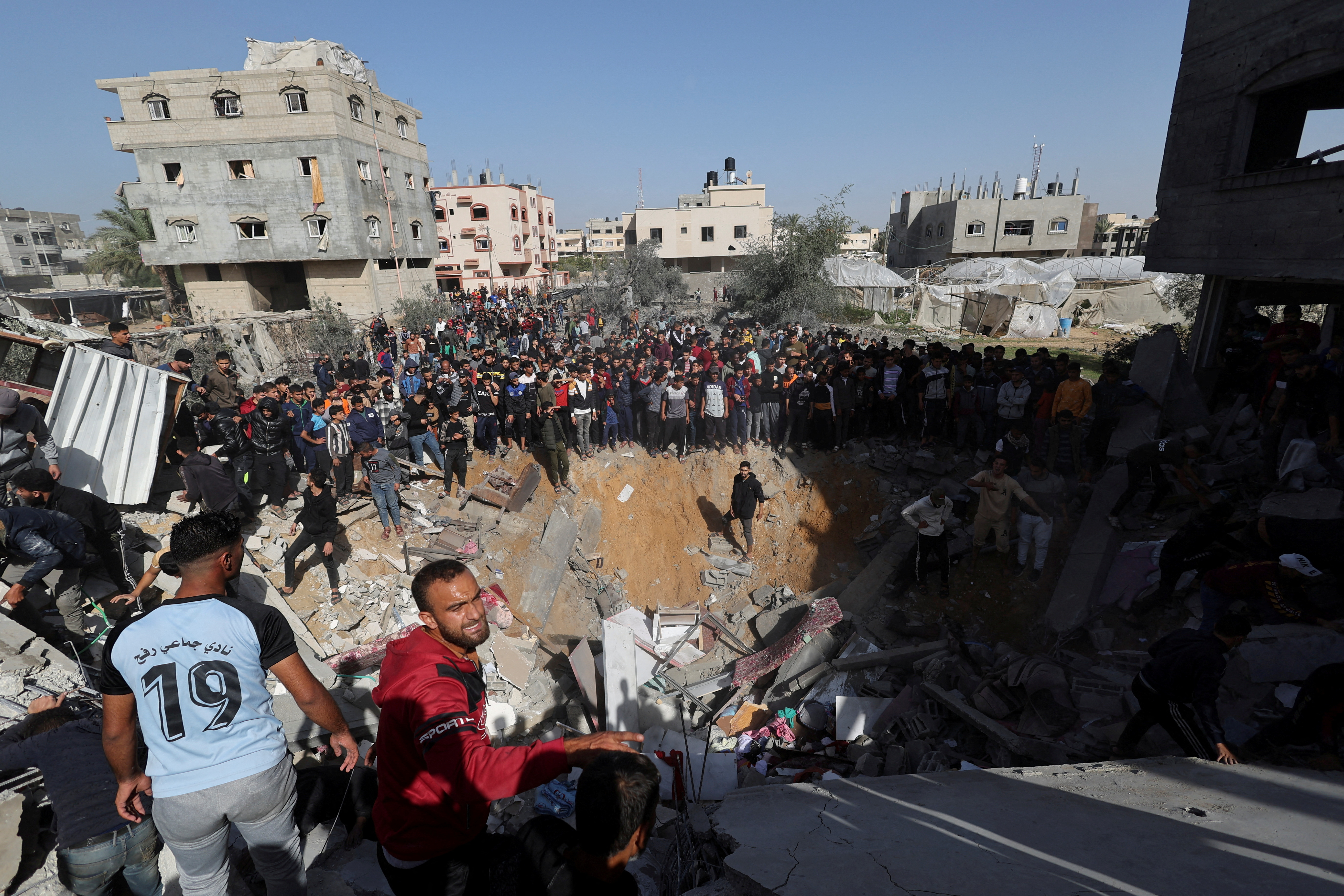 Warga Palestina berkumpul ketika yang lain mencari korban di lokasi serangan Israel terhadap sebuah rumah di Rafah, di tengah konflik yang sedang berlangsung antara Israel dan kelompok Islam Palestina Hamas, di Jalur Gaza selatan