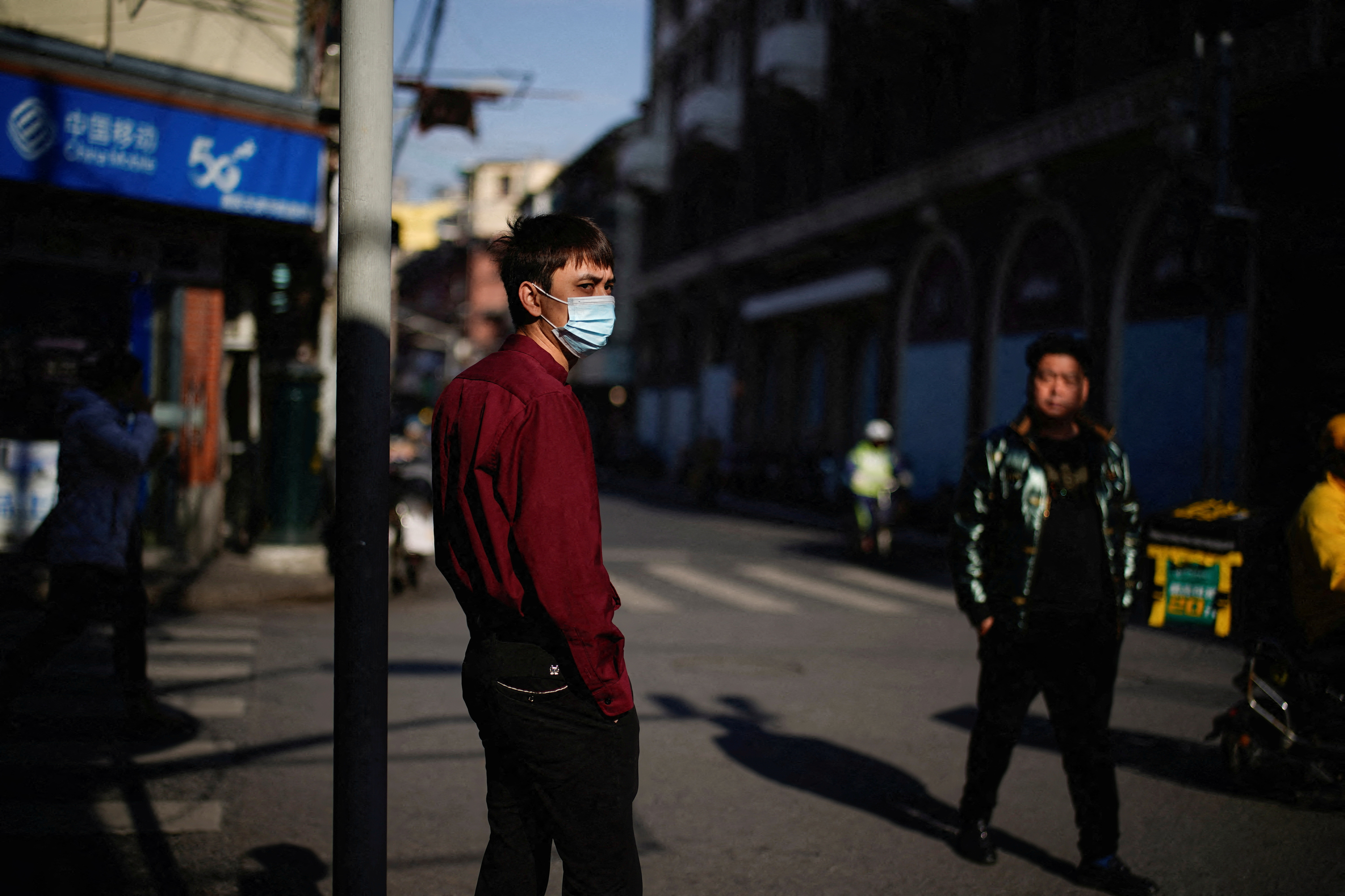A man wearing a protective mask stands on a street, following new cases of the coronavirus disease (COVID-19), in Shanghai