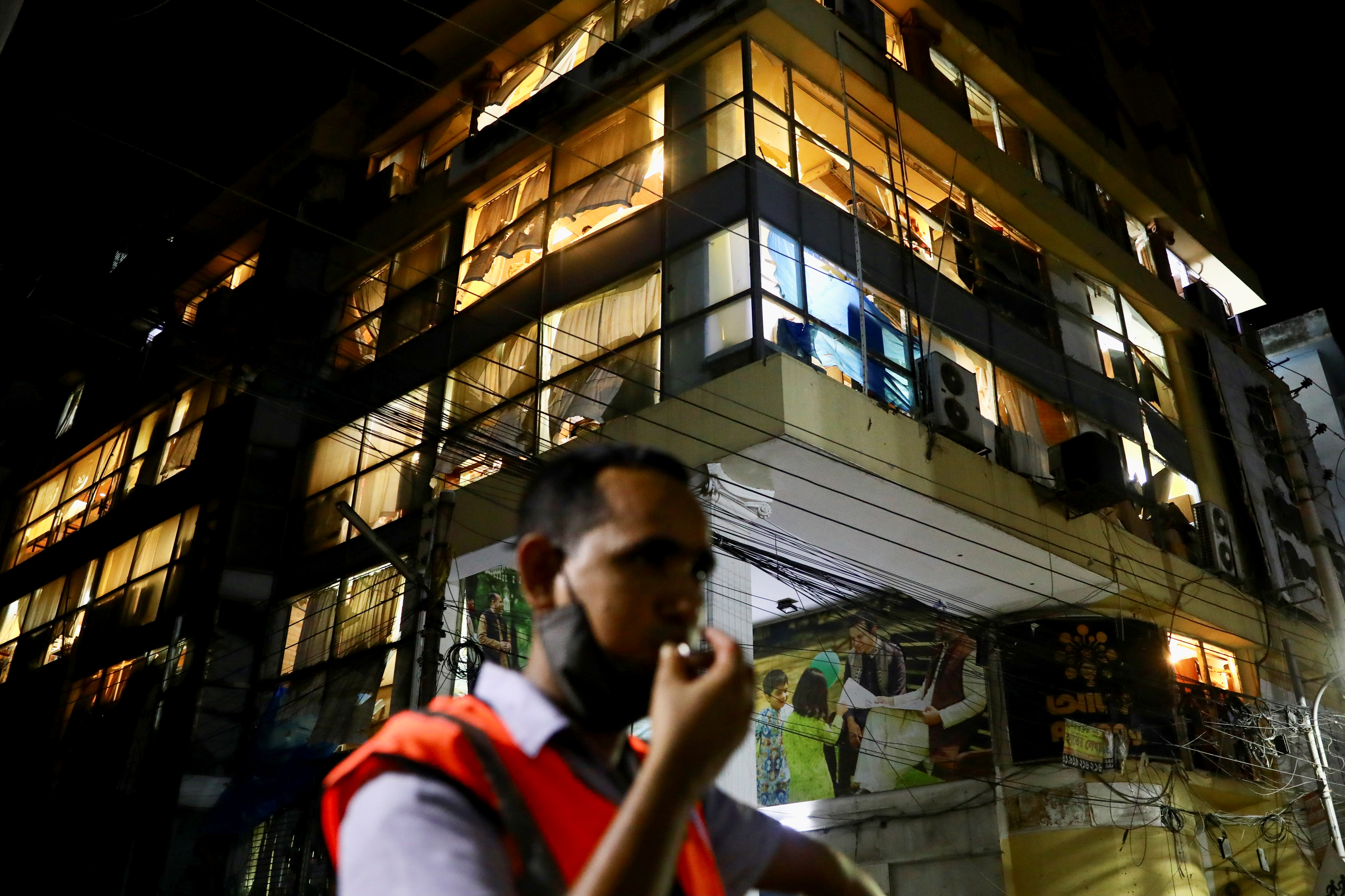 Broken windows of a multi-storey building are seen beside the site after a blast in a shop that killed several people in Dhaka