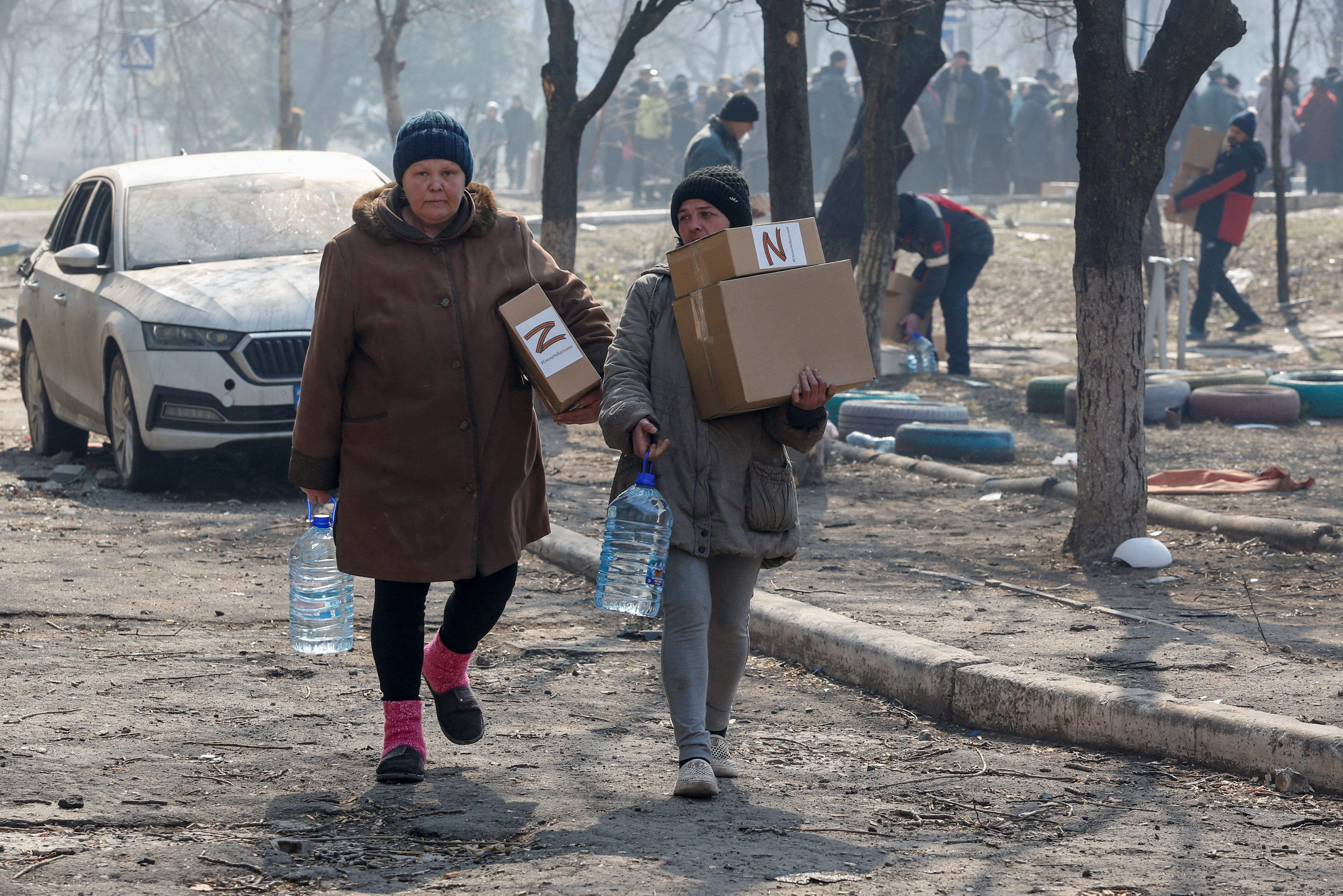 Local residents carry humanitarian aid delivered by Russian soldiers during Ukraine-Russia conflict, in the besieged southern port of Mariupol