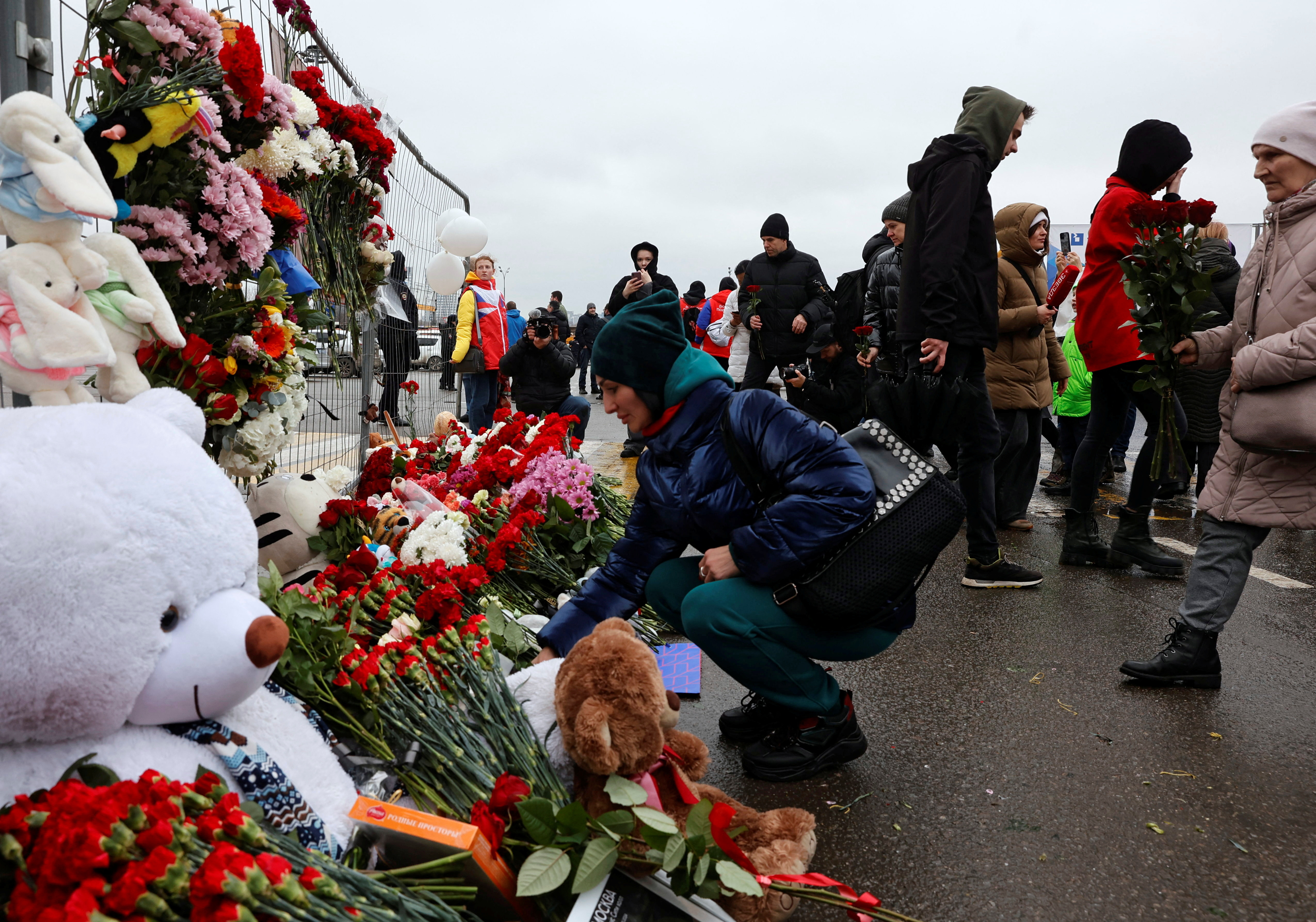 People lay flowers at a makeshift memorial to the victims of a shooting attack at a concert hall outside Moscow