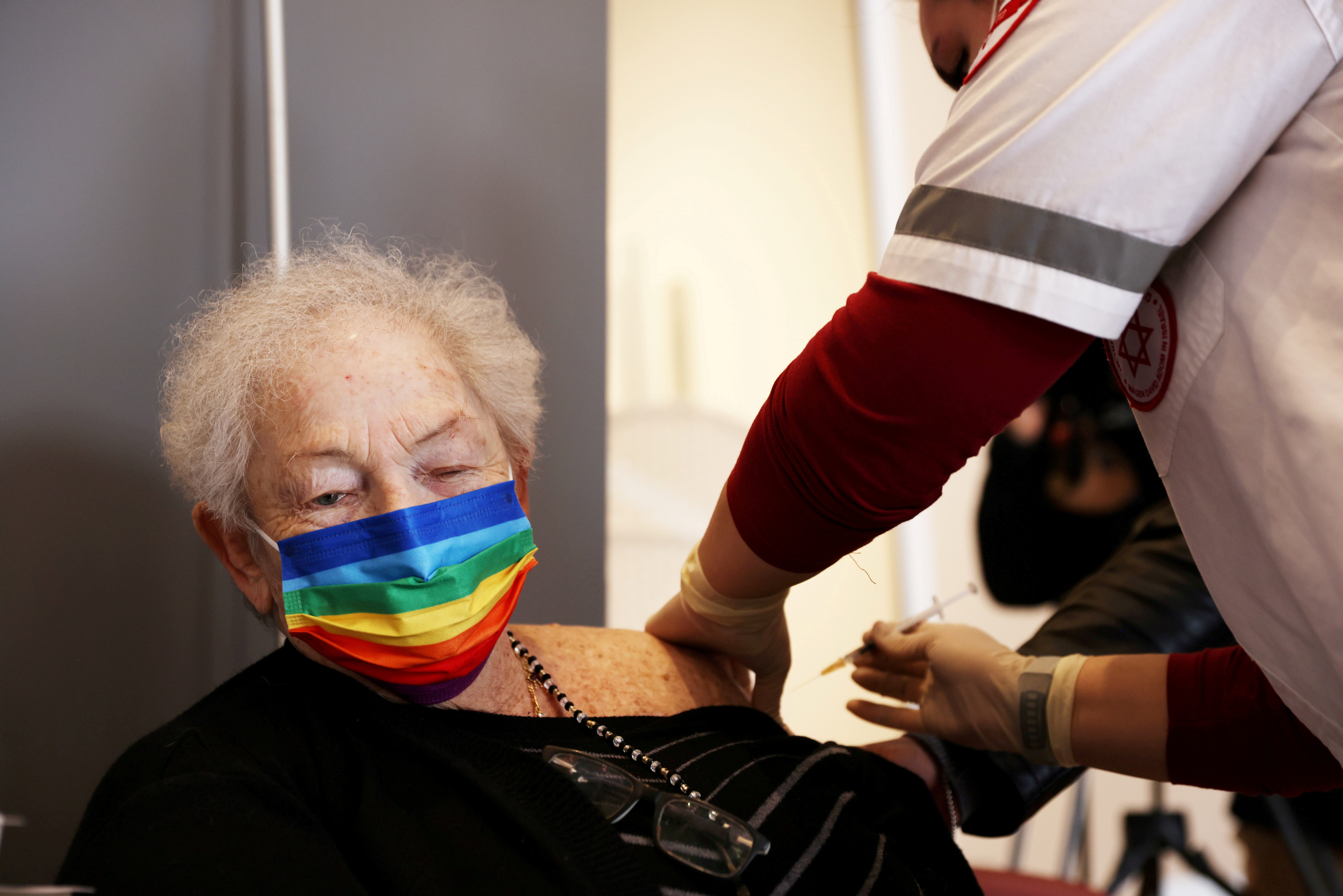 An elderly woman receives a booster shot of her vaccination against the coronavirus disease (COVID-19) at an assisted living facility, in Netanya