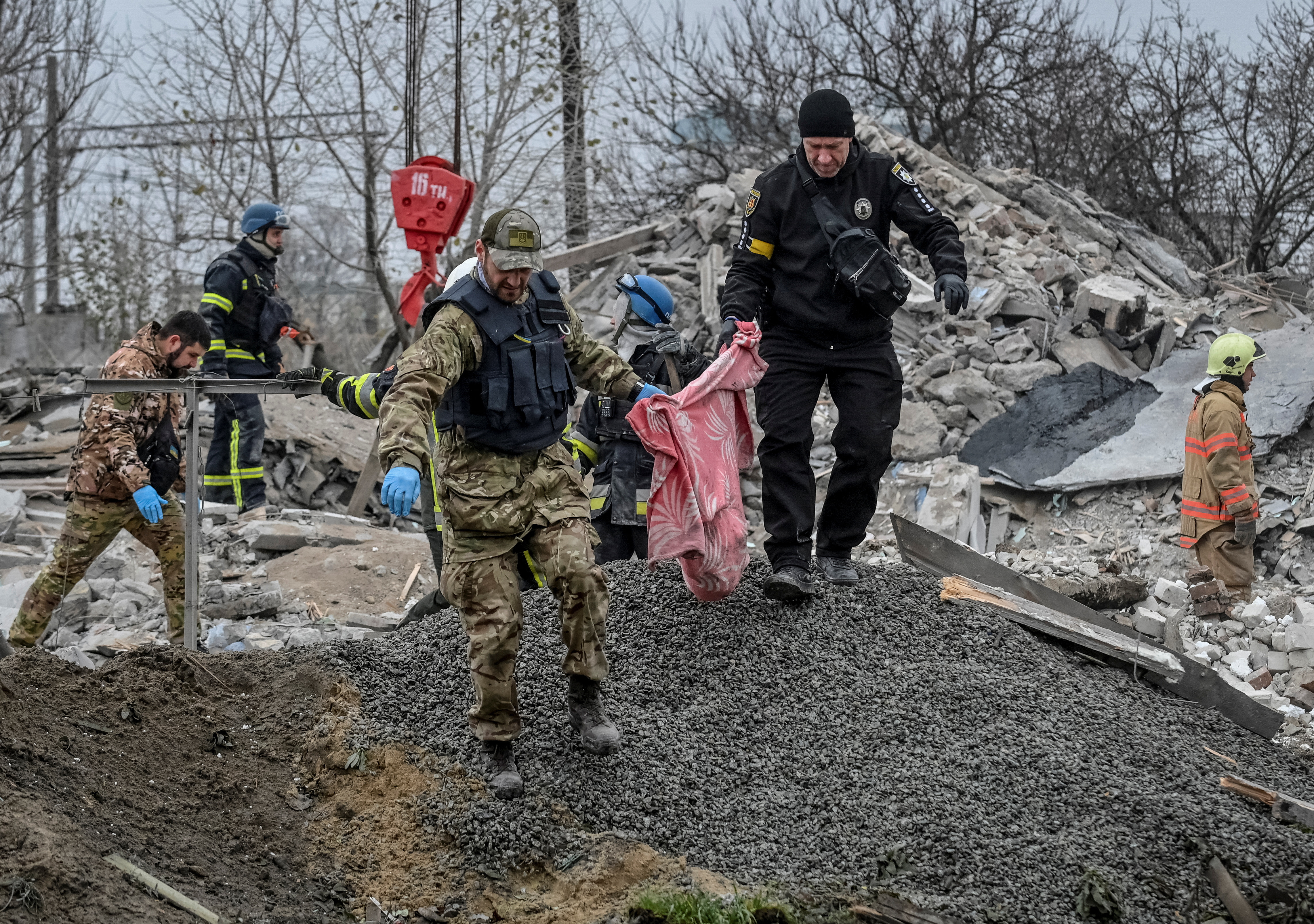 Police officers carry a fragments of the body found under debris of a residential house destroyed by a Russian missile strike in the town of Vilniansk